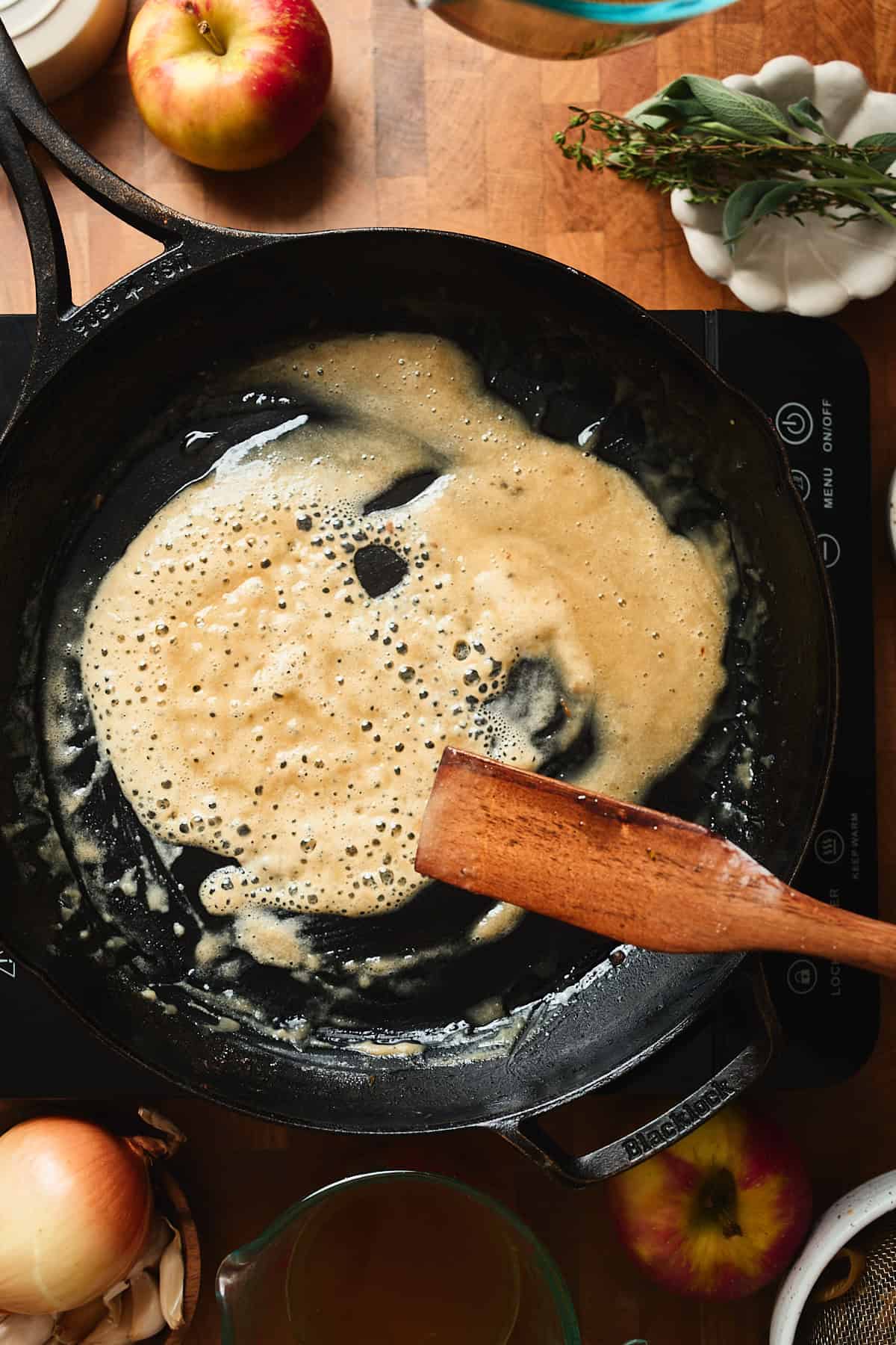 Roux forming in a skillet with a wooden scraper spoon mixing it.