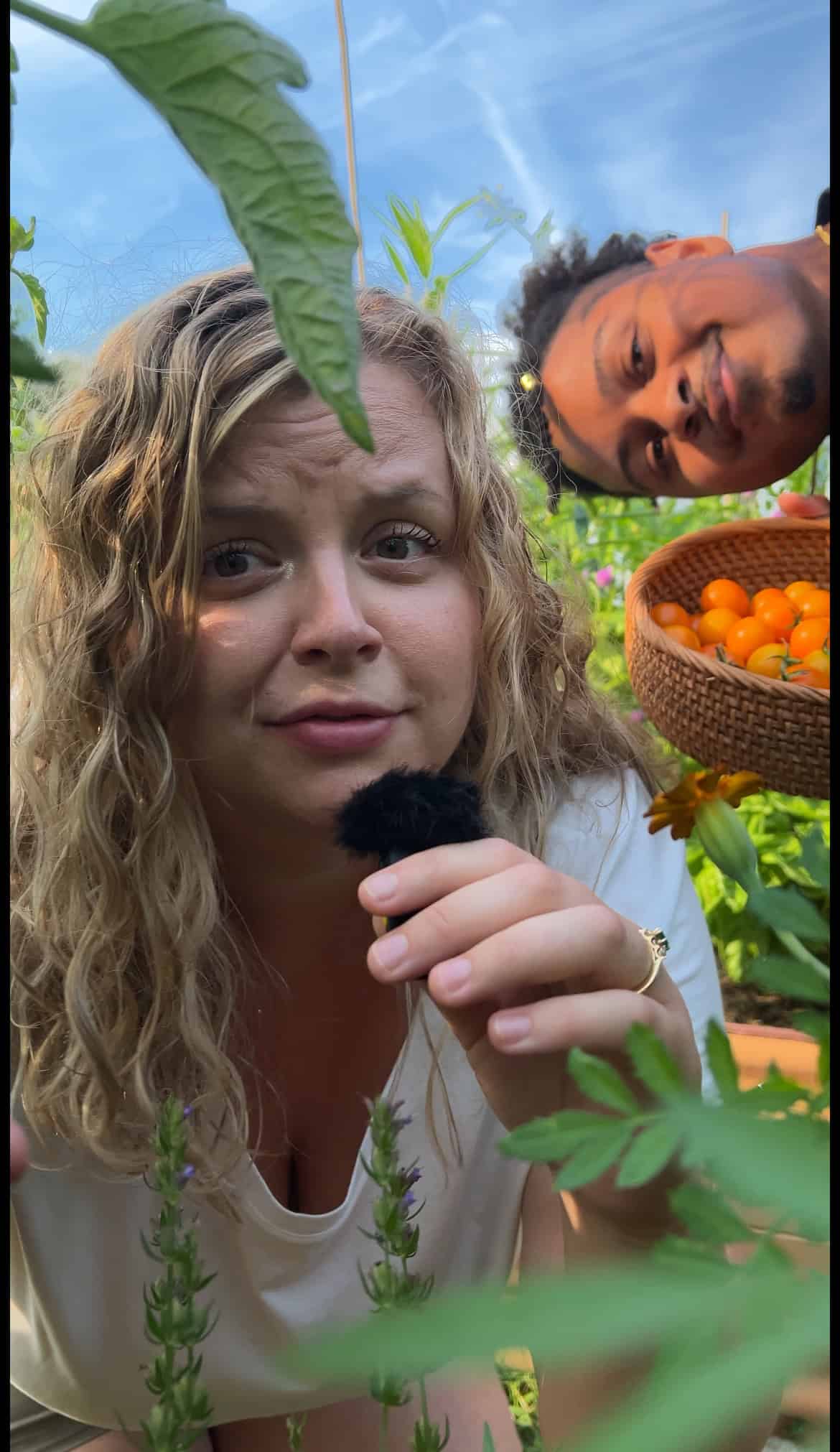 Man and woman in a garden filming a video.