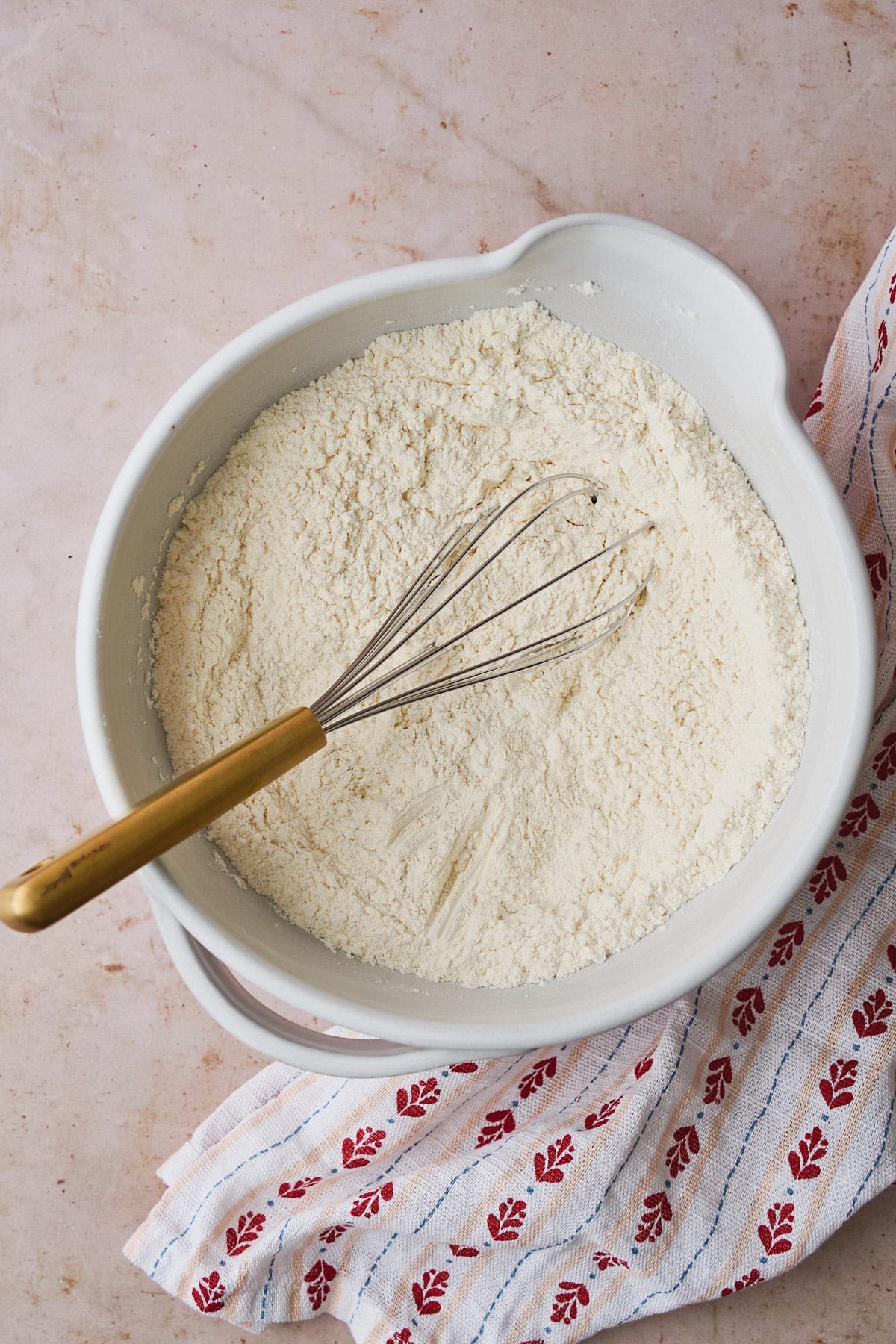 Dry ingredients of flour, cardamom, and salt in a mixing bowl with a whisk.