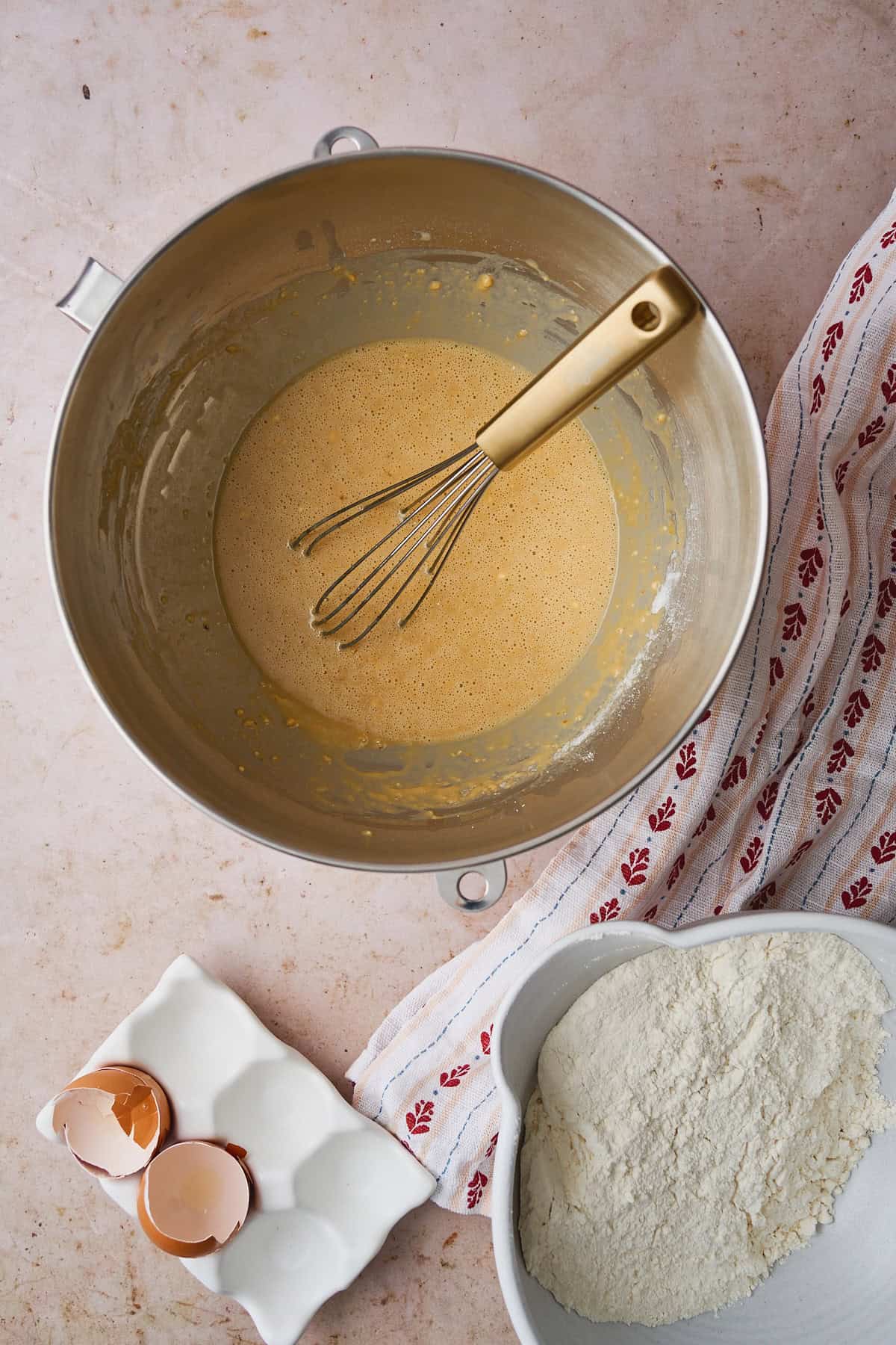 Some of the flour mixture added to the milk and butter mixture in a mixing bowl.