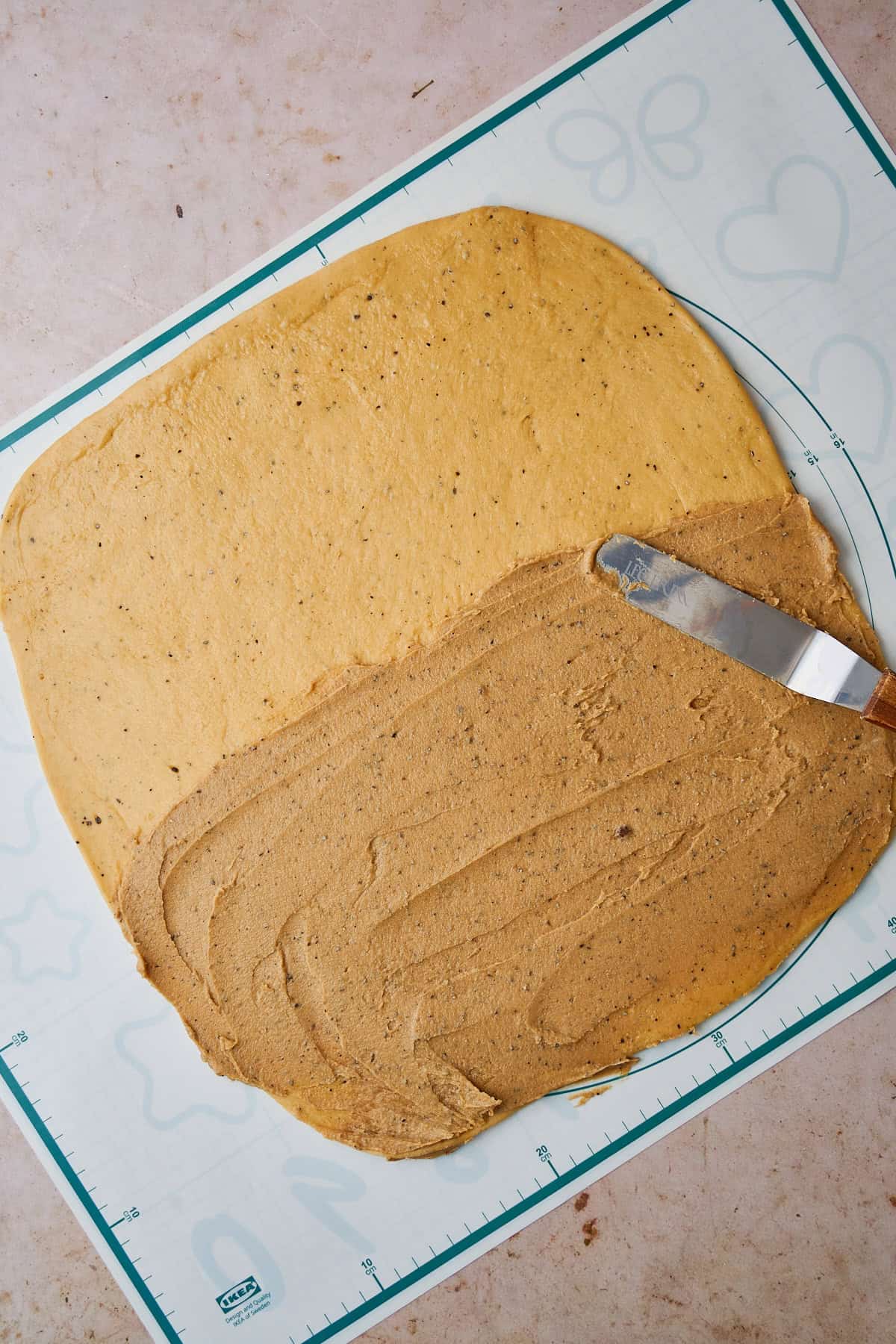 Spreading brown sugar, butter filling on half of a cardamom bun dough.