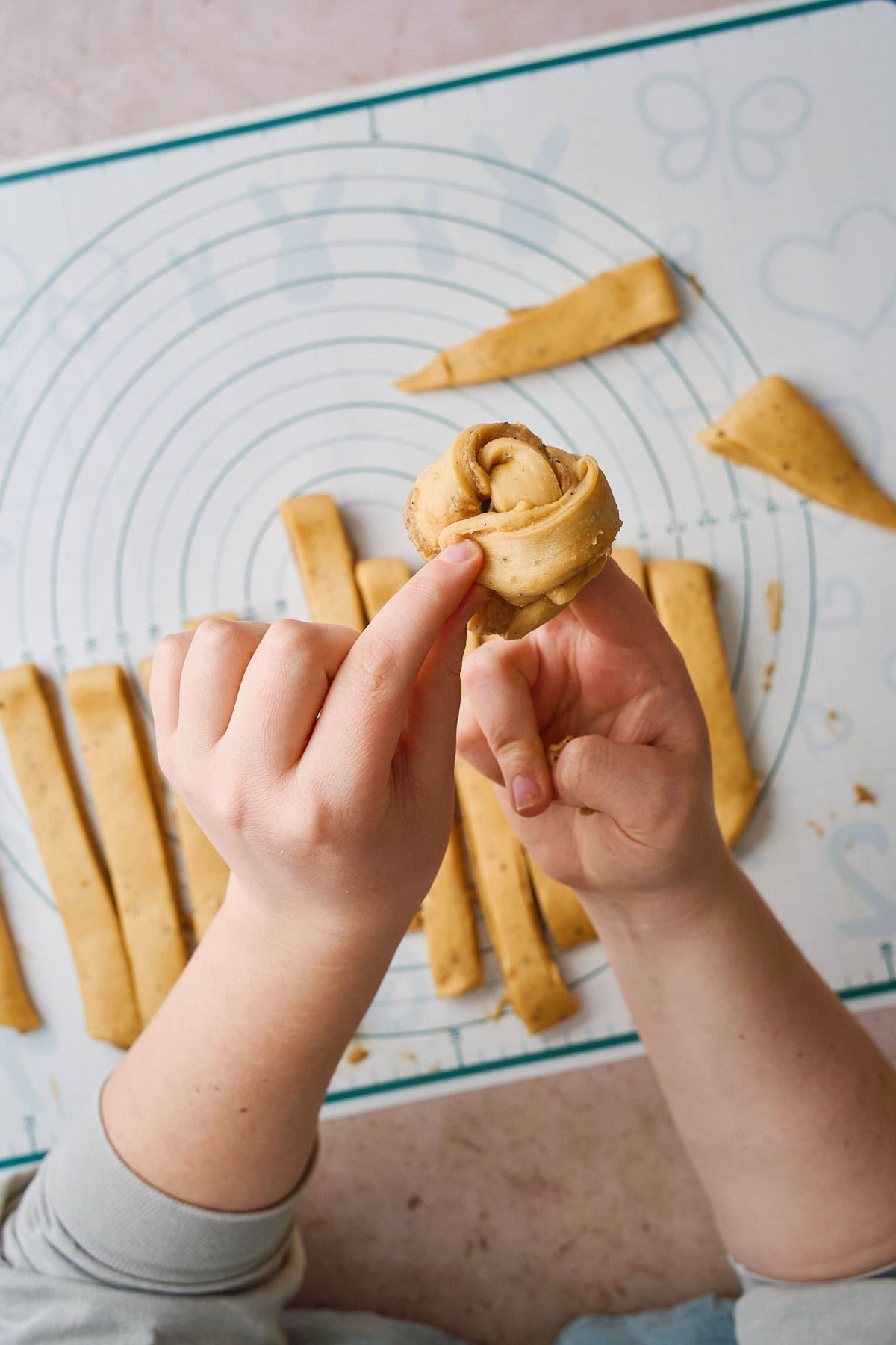 Twisting a bun around fingers for a second time to create a knot shape.