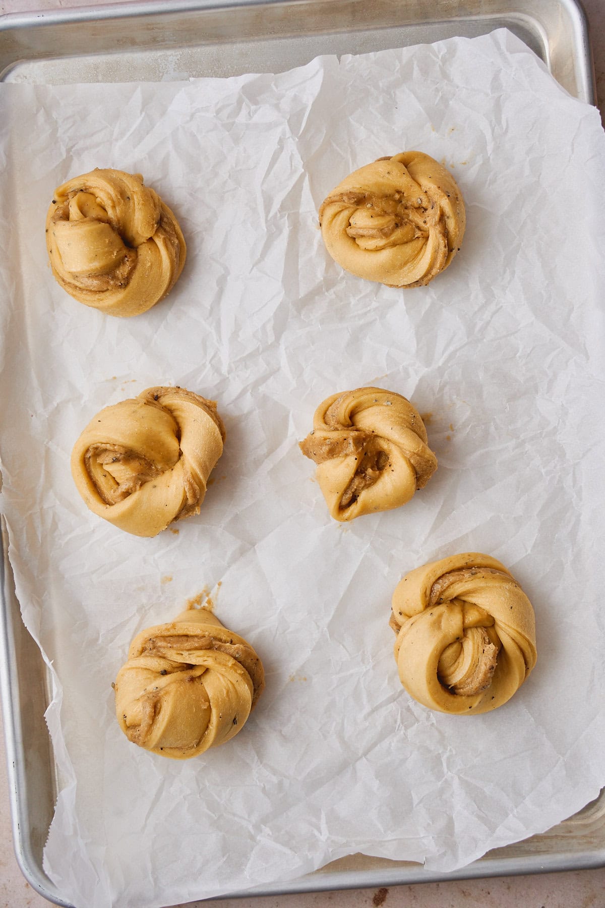 Cardamom buns shaped on a parchment paper and getting ready for a second rise.