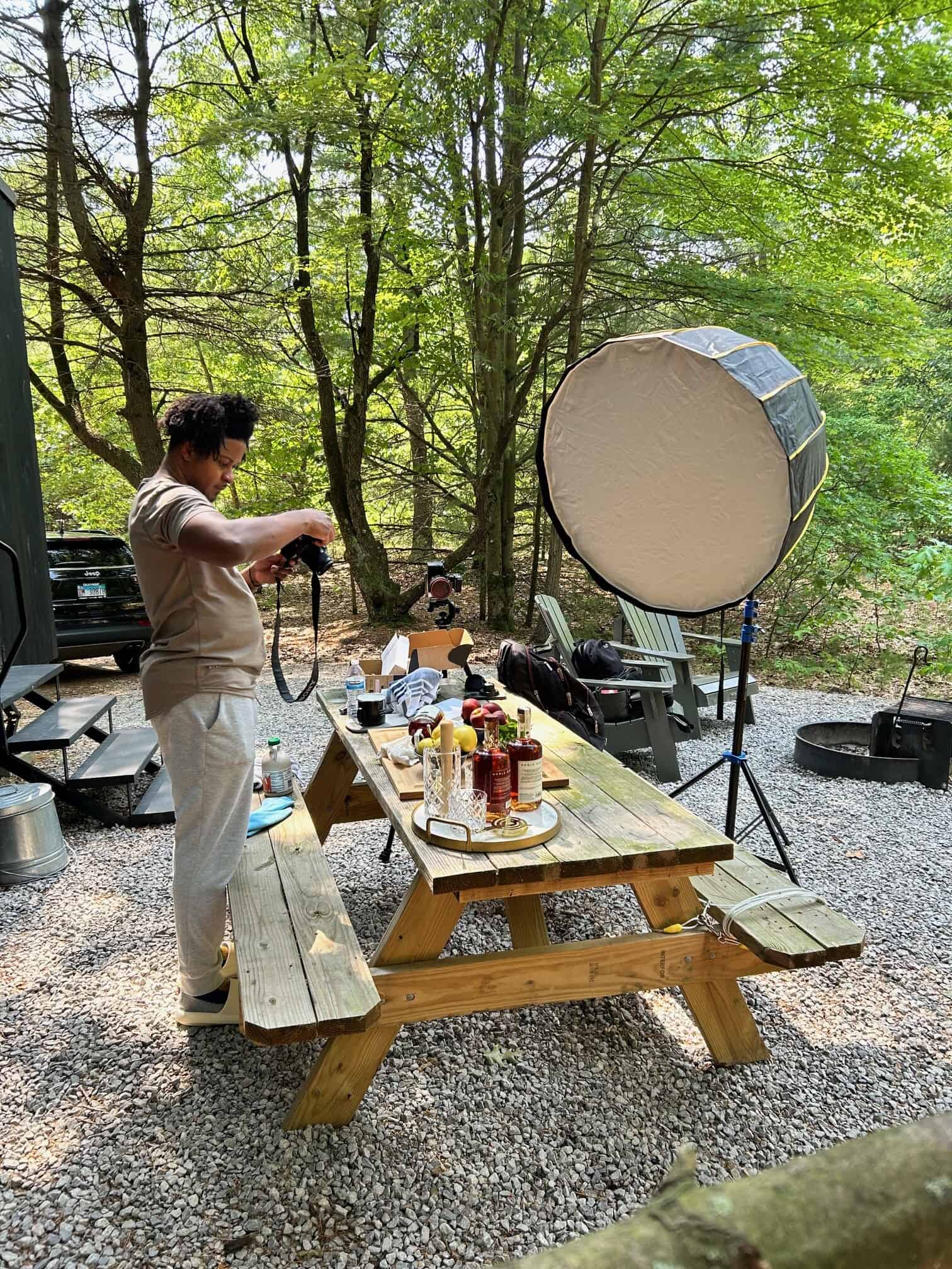 Chamere outside in the forest with a cocktail scene set up and camera gear surrounding him.