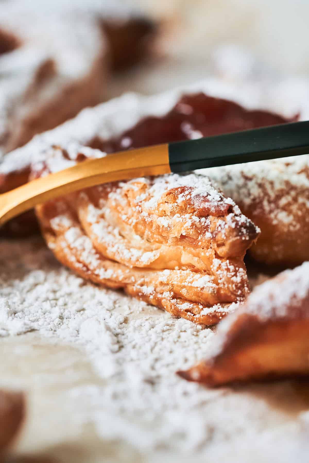 Buttery, flaky pastry folded into a croissant shape dusted with powdered sugar, ready for baking.