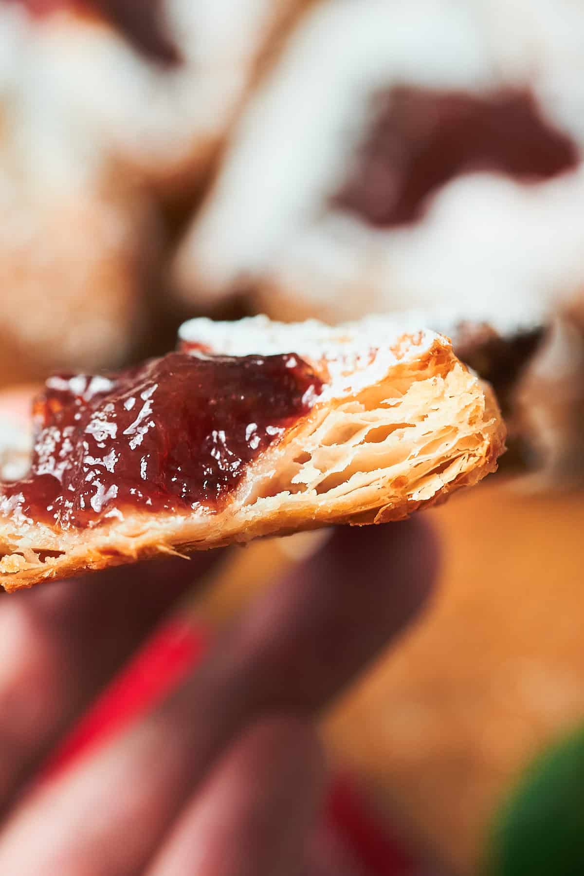 Baked puff pastry treat with jam bitten into to show the layers of the pastry.