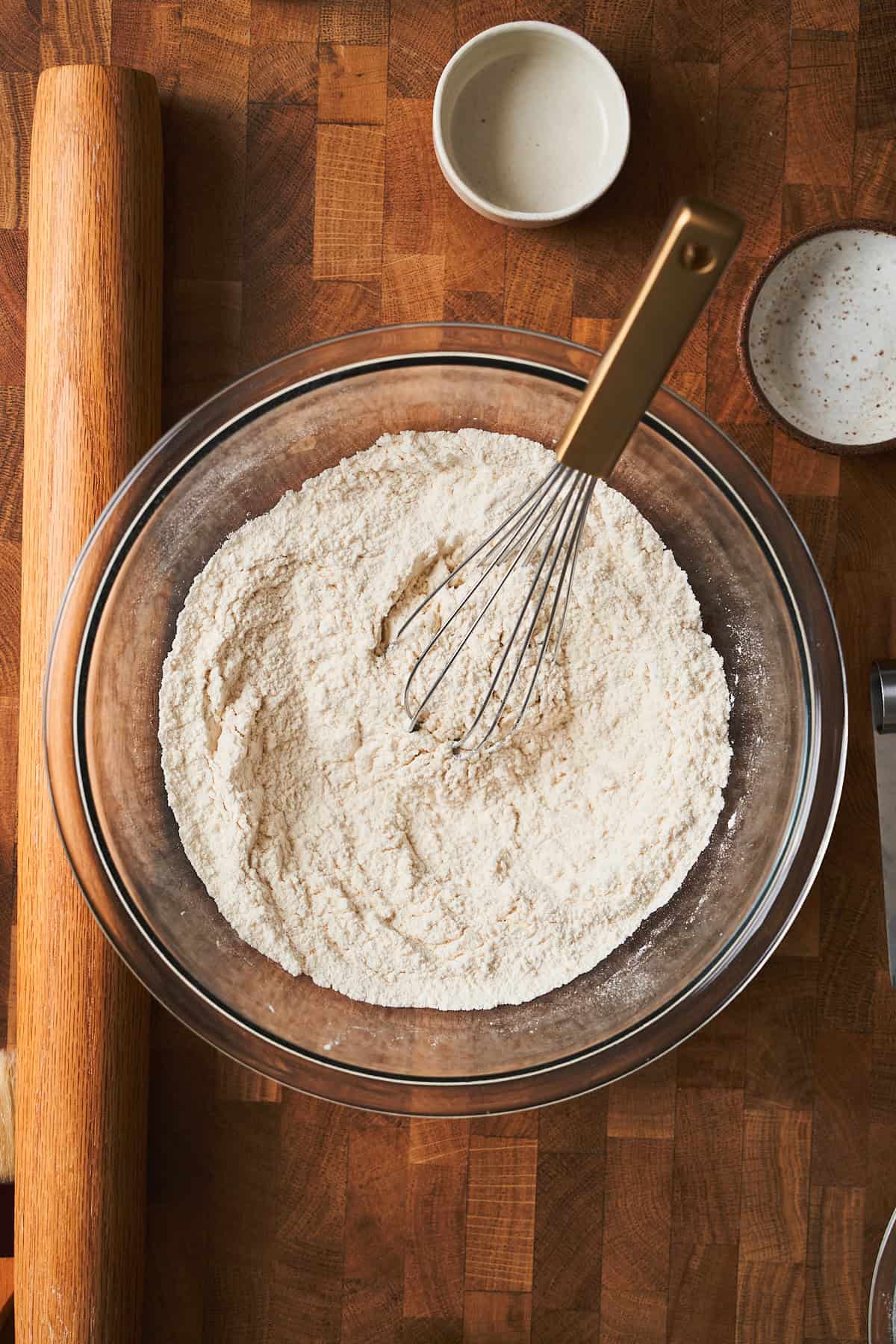 Bowl of whisked flour and other ingredients on a wooden surface.