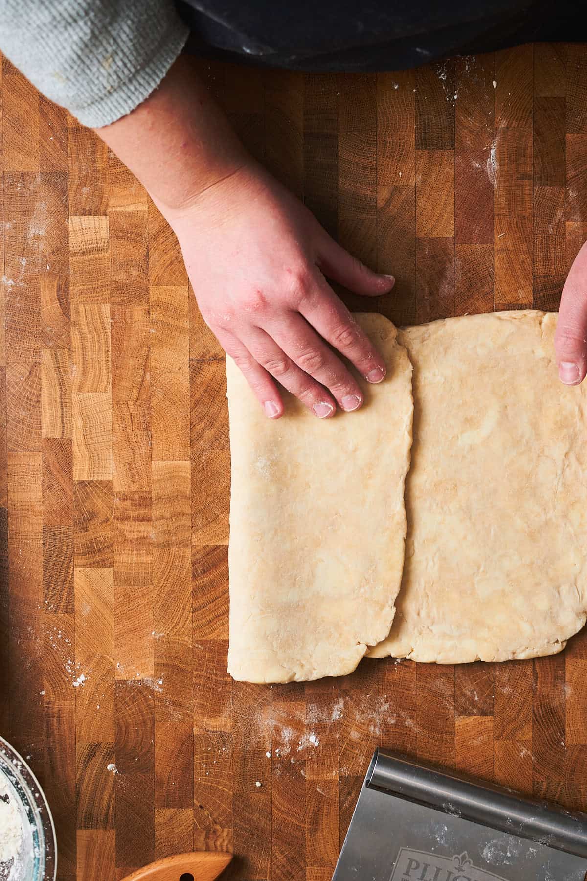 Hands folding dough like a business letter in thirds.