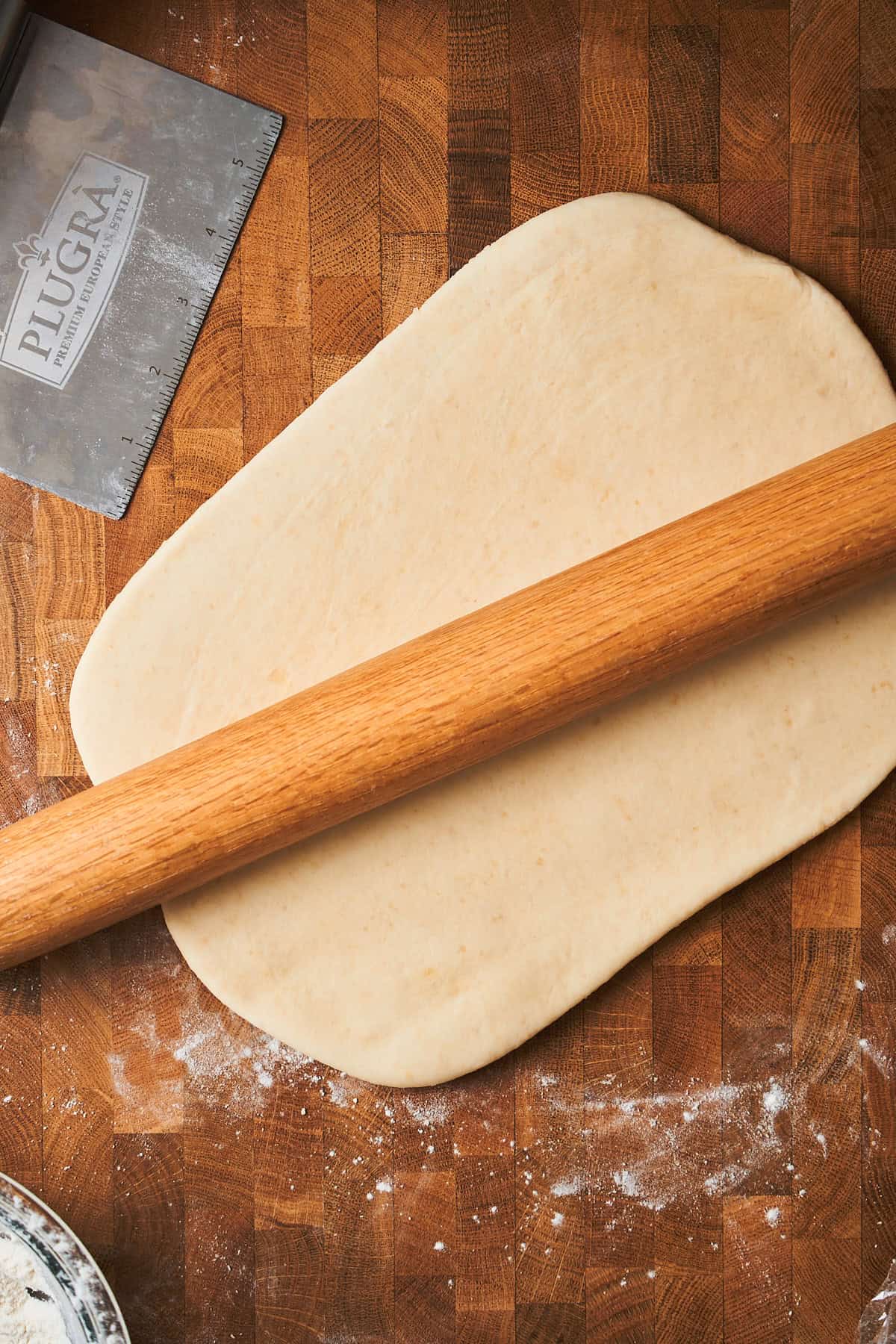Flat and rolled out dough on floured work surface with a rolling pin on top.