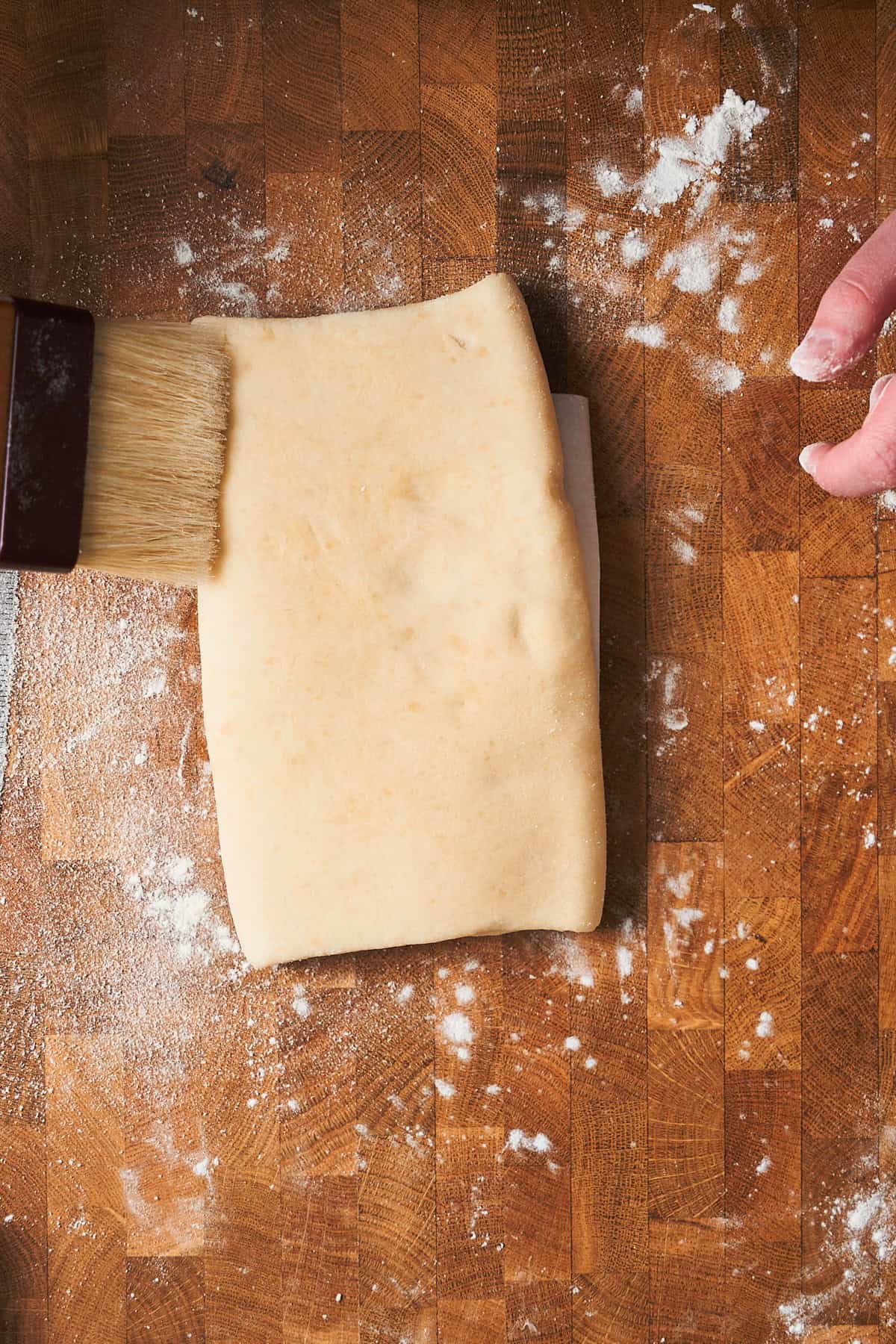 Brushing extra flour off of puff pastry.