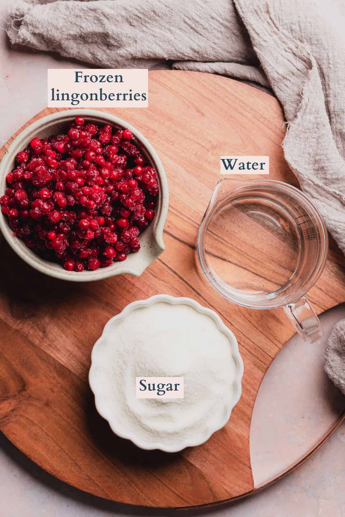 Ingredients laid out to make homemade lingonberry jam or sauce, labeled to denote each ingredient.