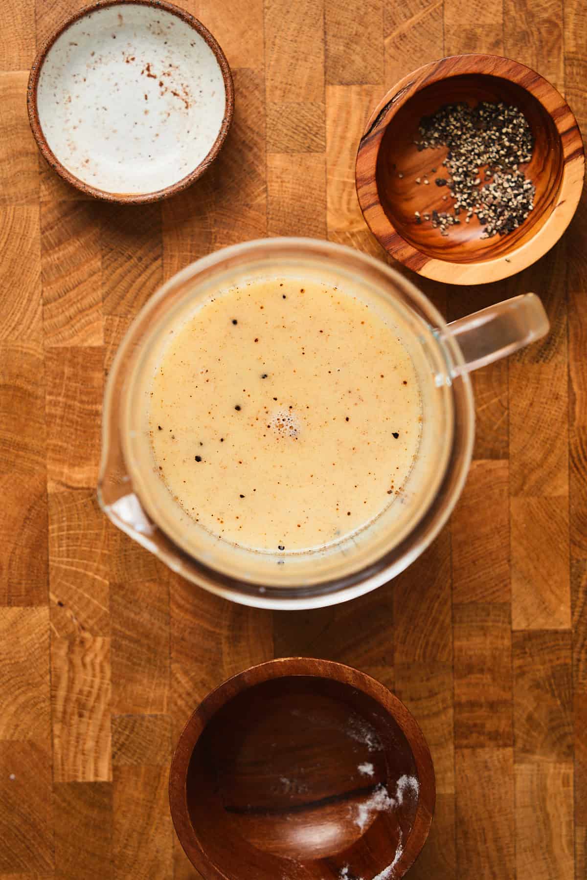 Melted butter in milk with salt, pepper, and nutmeg in a glass container.