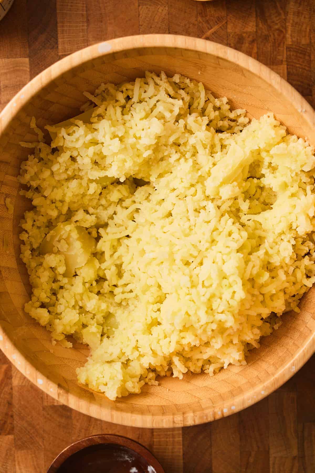 Riced potatoes in a wooden mixing bowl.