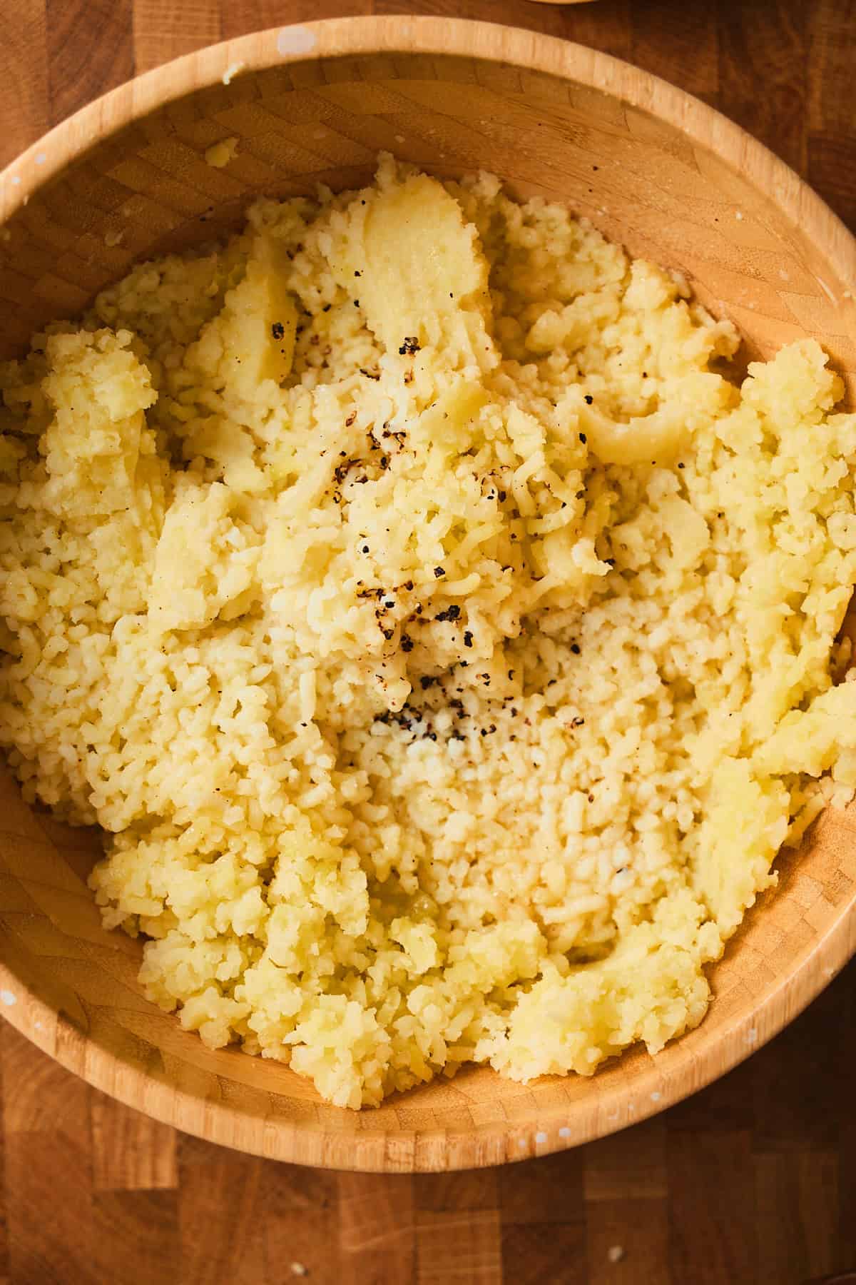 Riced potatoes in a bowl with hot cream and butter mixture added.
