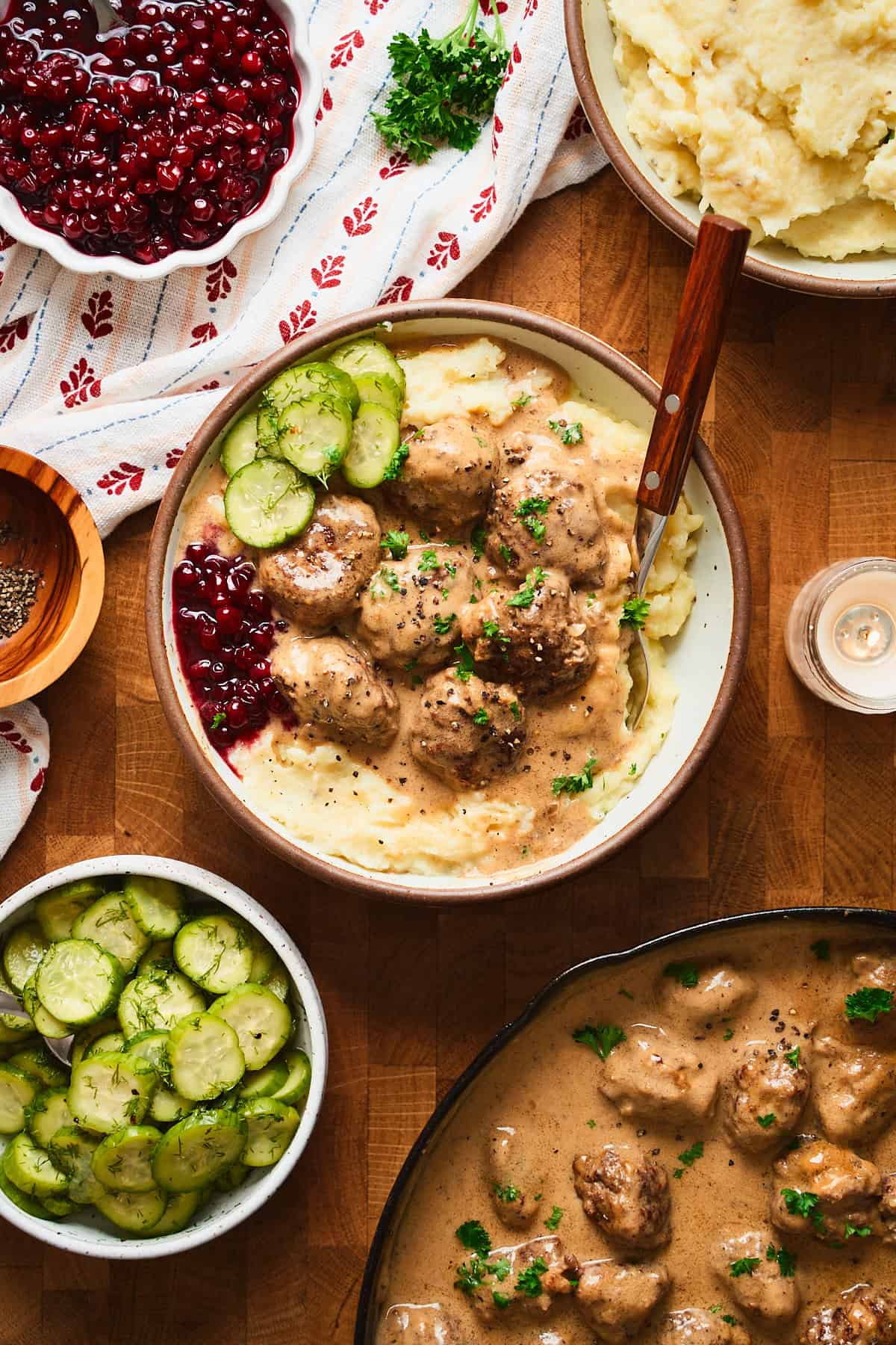 Bowl of Swedish meatballs with mashed potatoes, lingonberries, and cucumber salad.