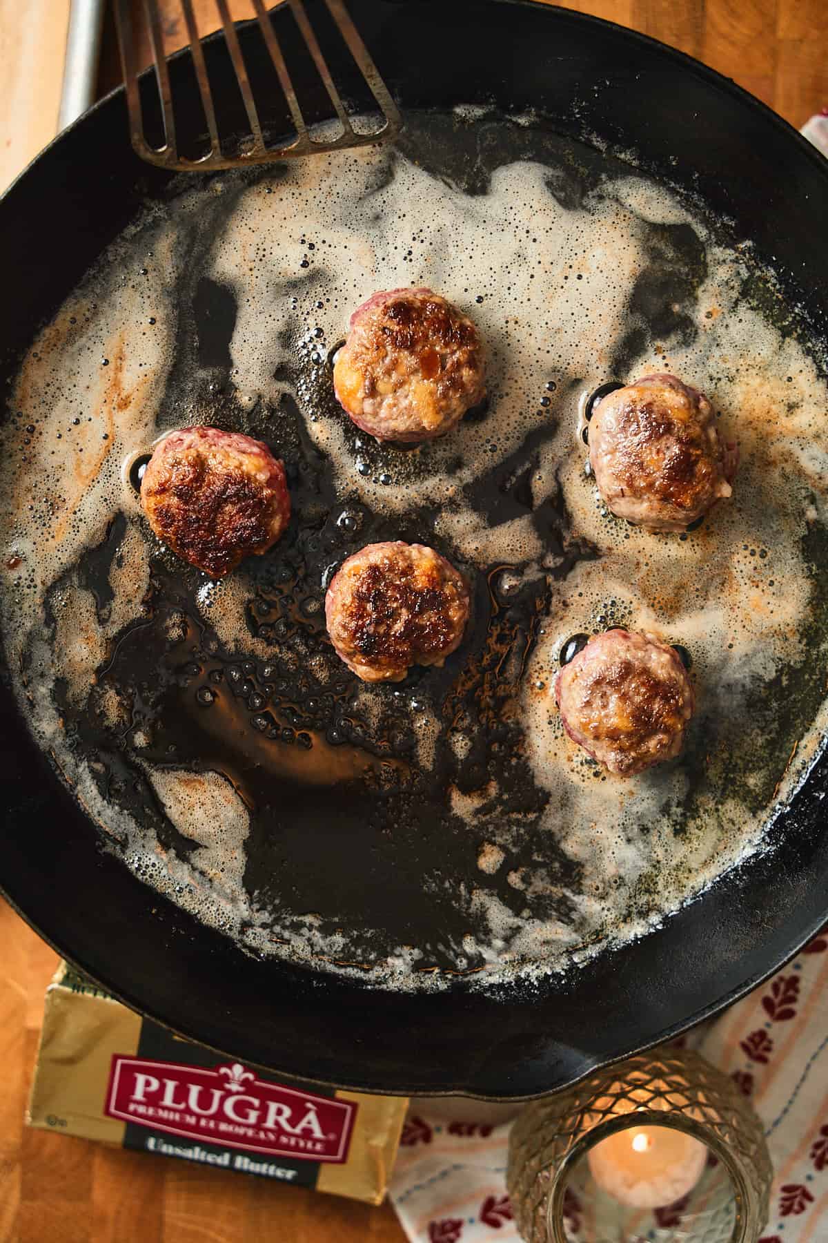 Meatballs cooking and getting nice and brown in hot butter in a skillet.