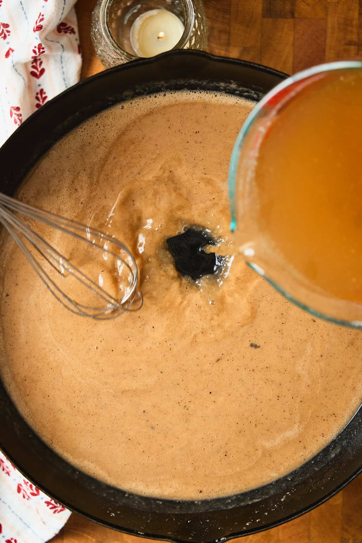 Whisking in beef broth to a skillet to make Swedish meatball gravy.