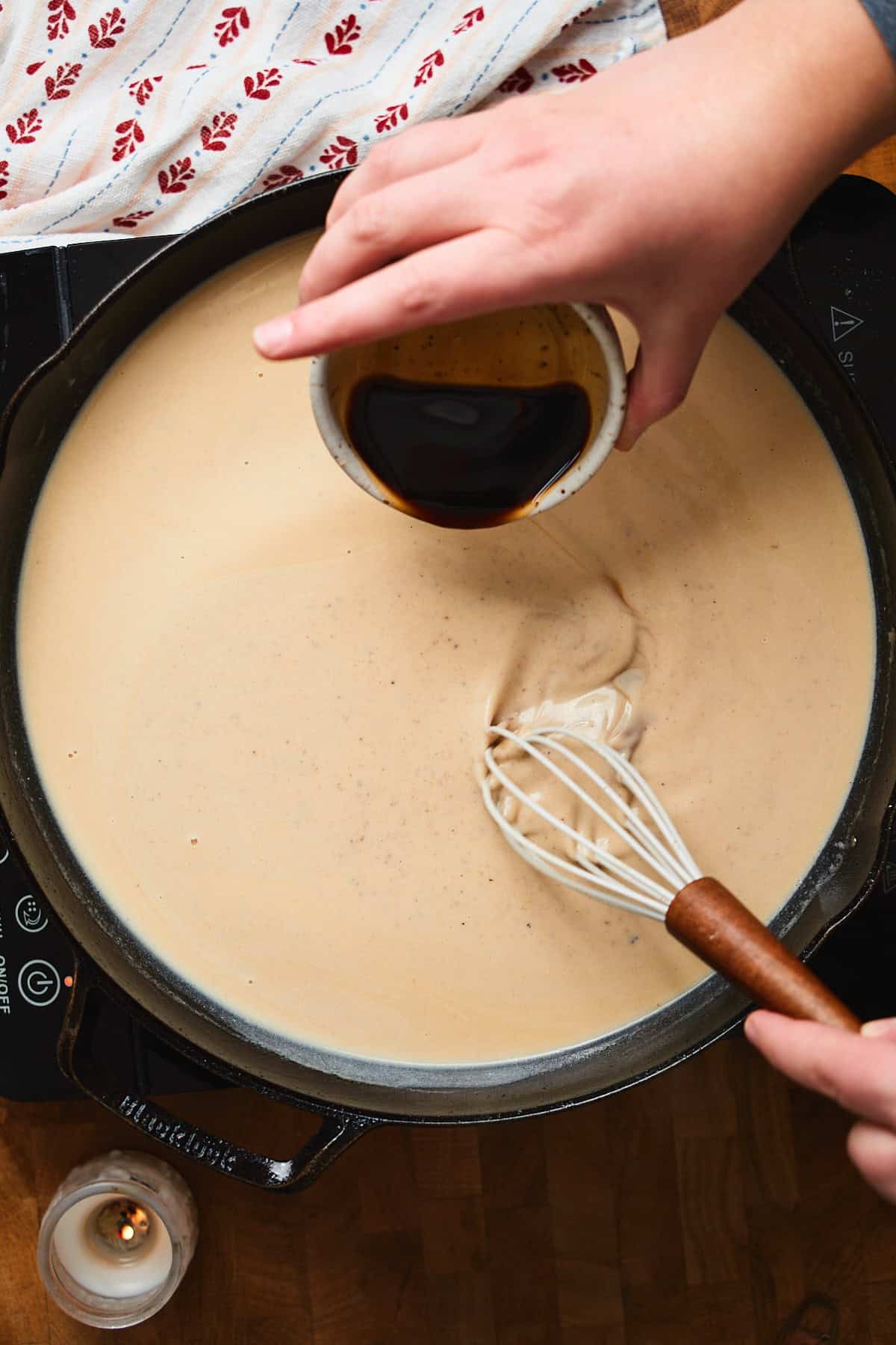 Gravy beginning to form in a skillet with cream and Worcestershire sauce added.