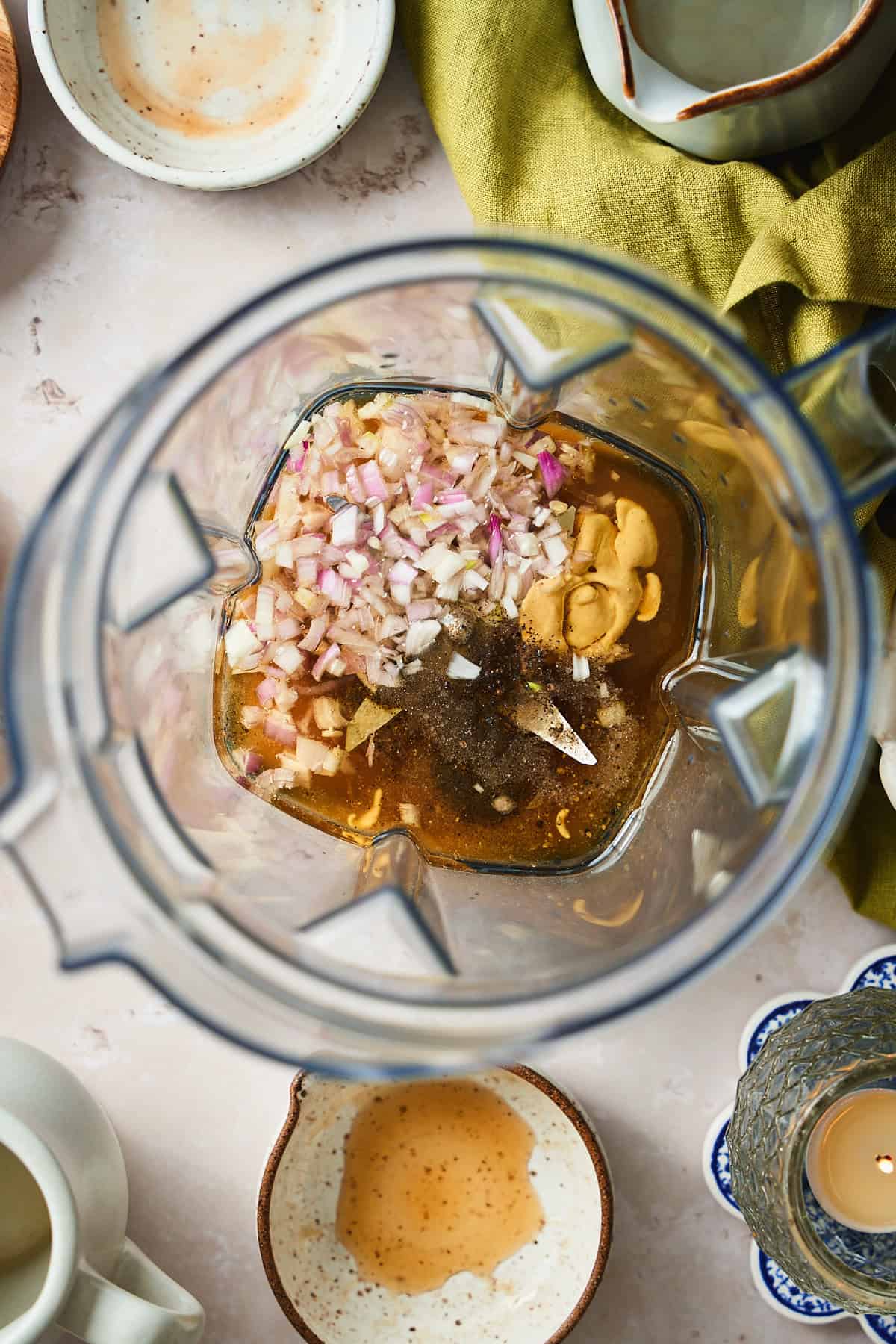 Oil, maple syrup, Dijon mustard, shallots, salt, pepper, and apple cider in a blender getting ready to turn into dressing.