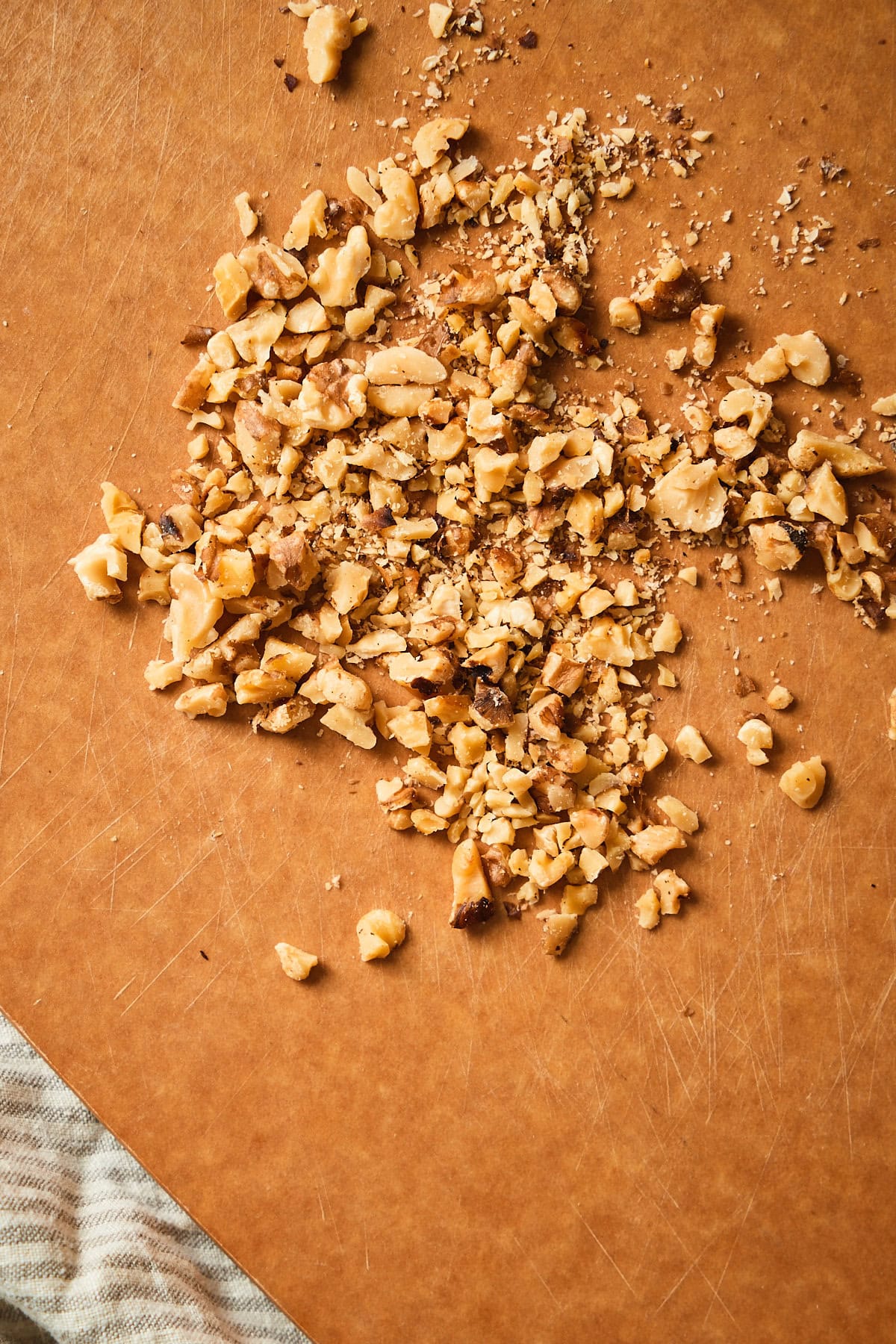 Chopped walnut pieces on a wood cutting board.