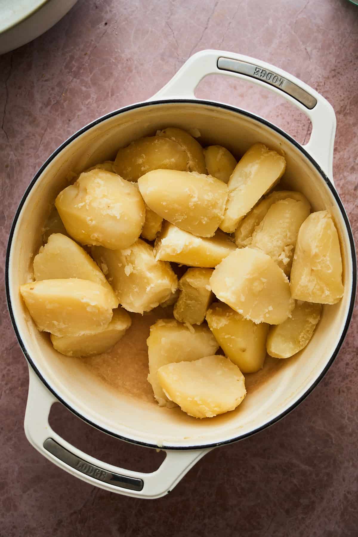 Boiled potato chunks that are in a pot.