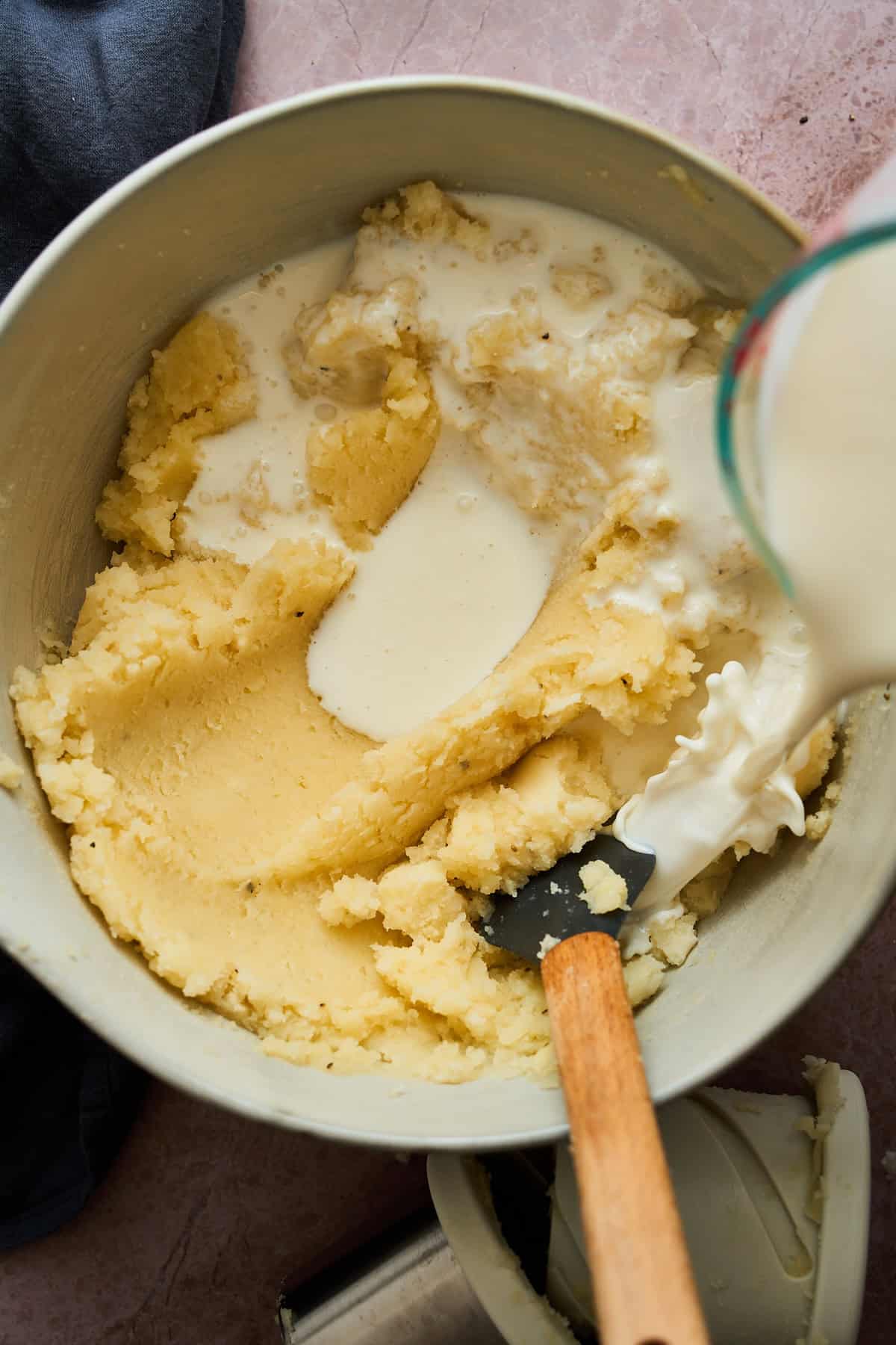 Pouring buttermilk into creamy mashed potatoes.