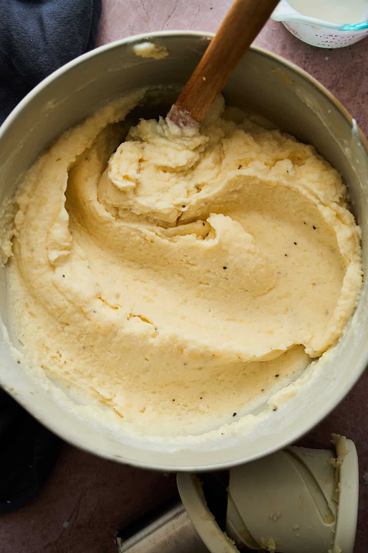 Creamy buttermilk mashed potatoes being combined in a bowl with a rubber spatula.
