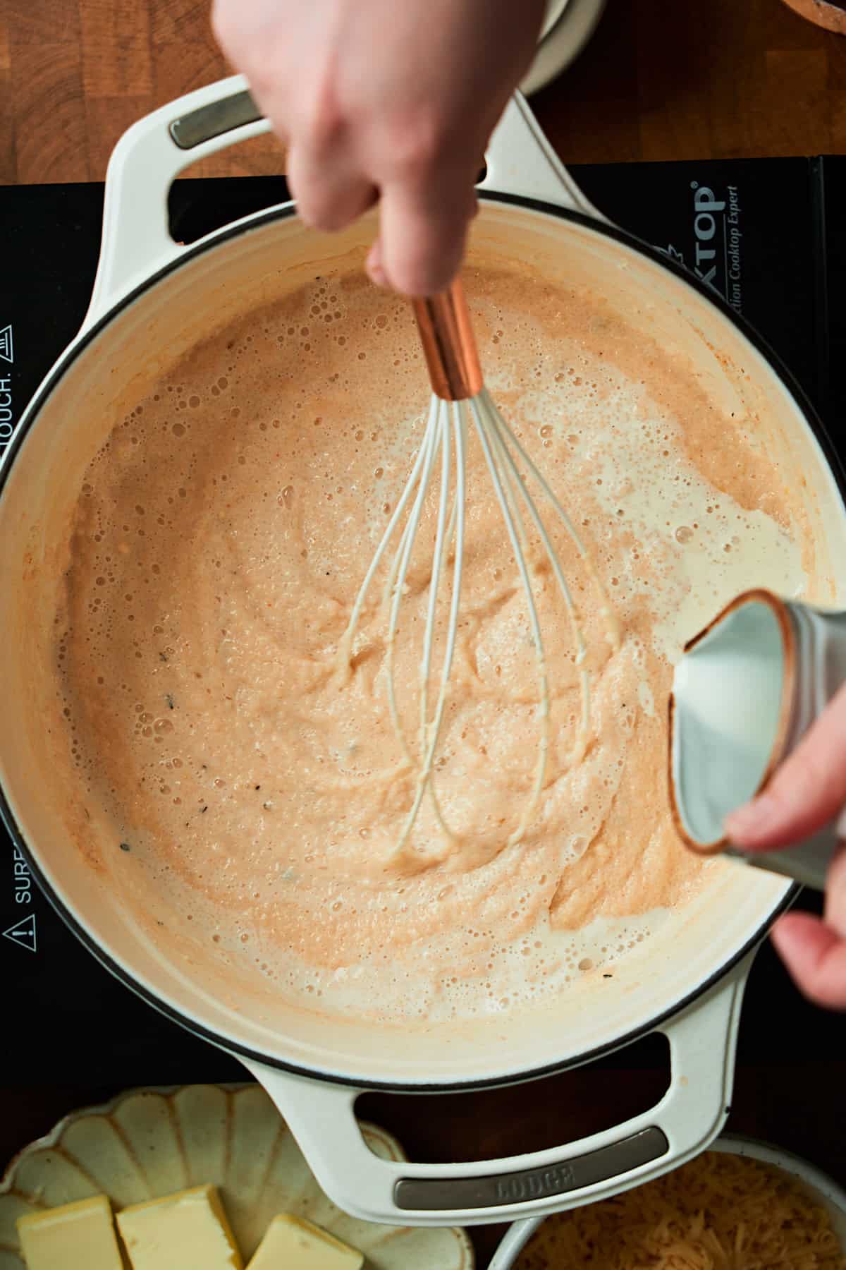 Pouring cream into creamy grits to loosen them up.