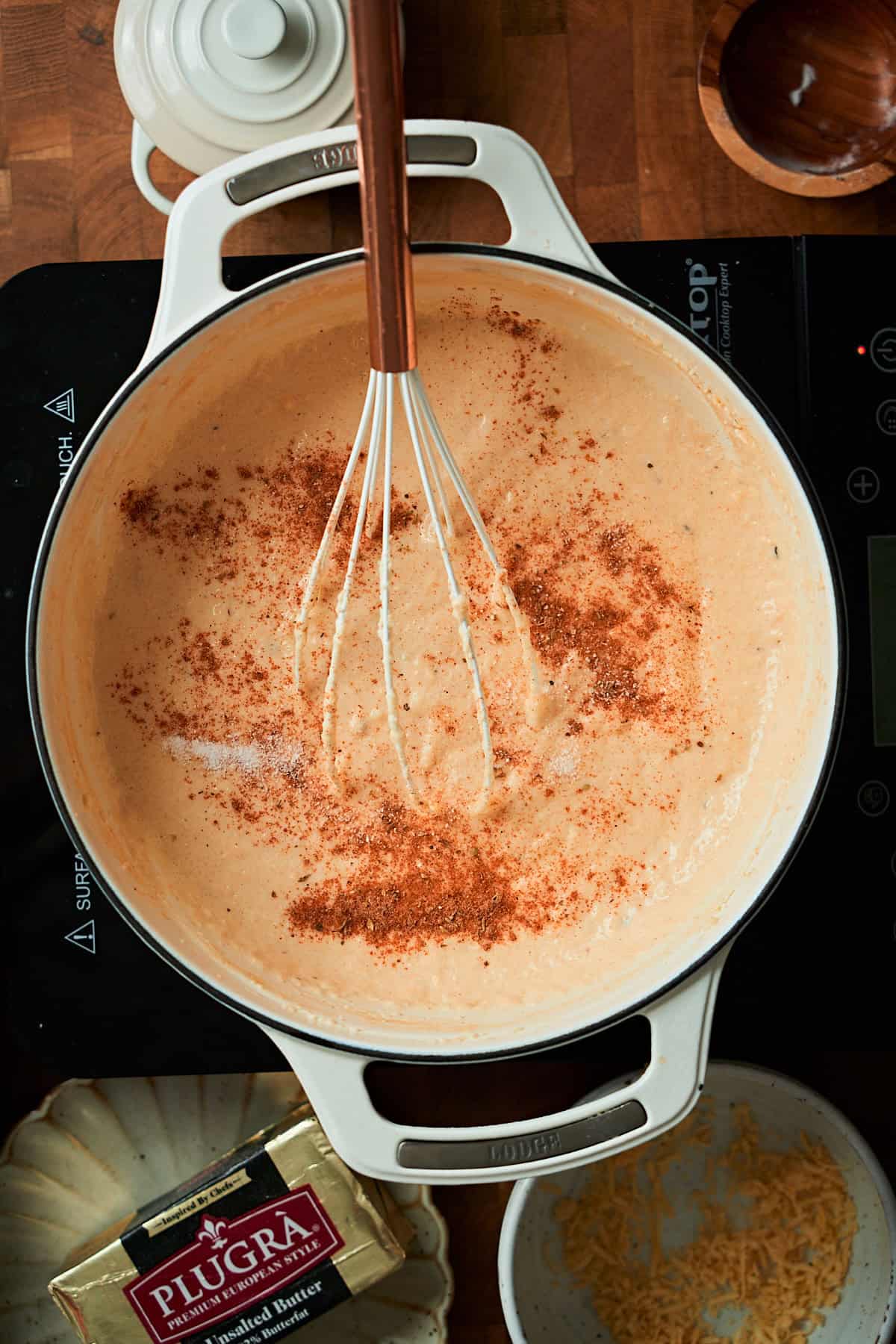 Cajun seasoning, salt, and pepper added to grits in a Dutch oven.