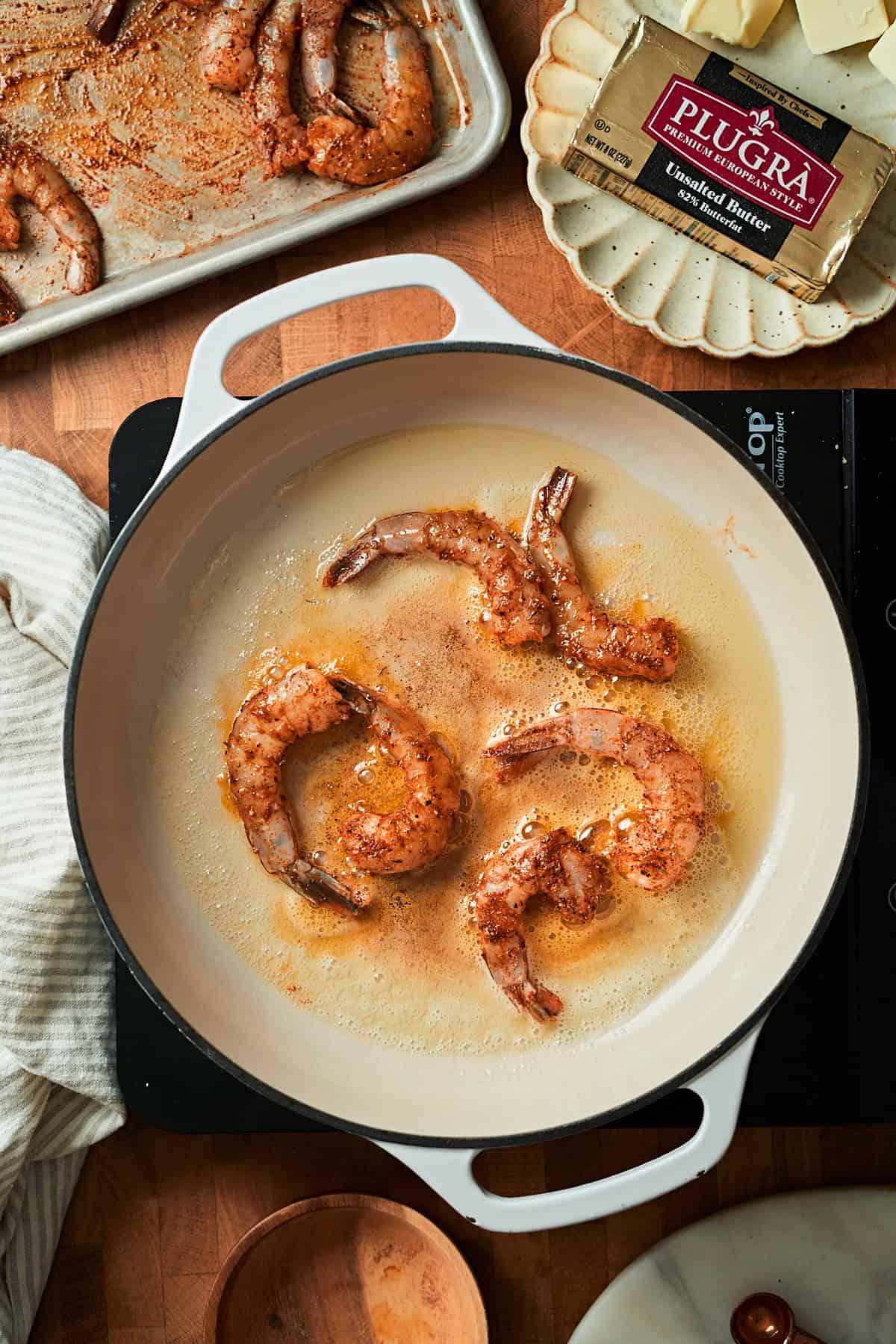 Adding raw shrimp to a skillet with oil and butter.