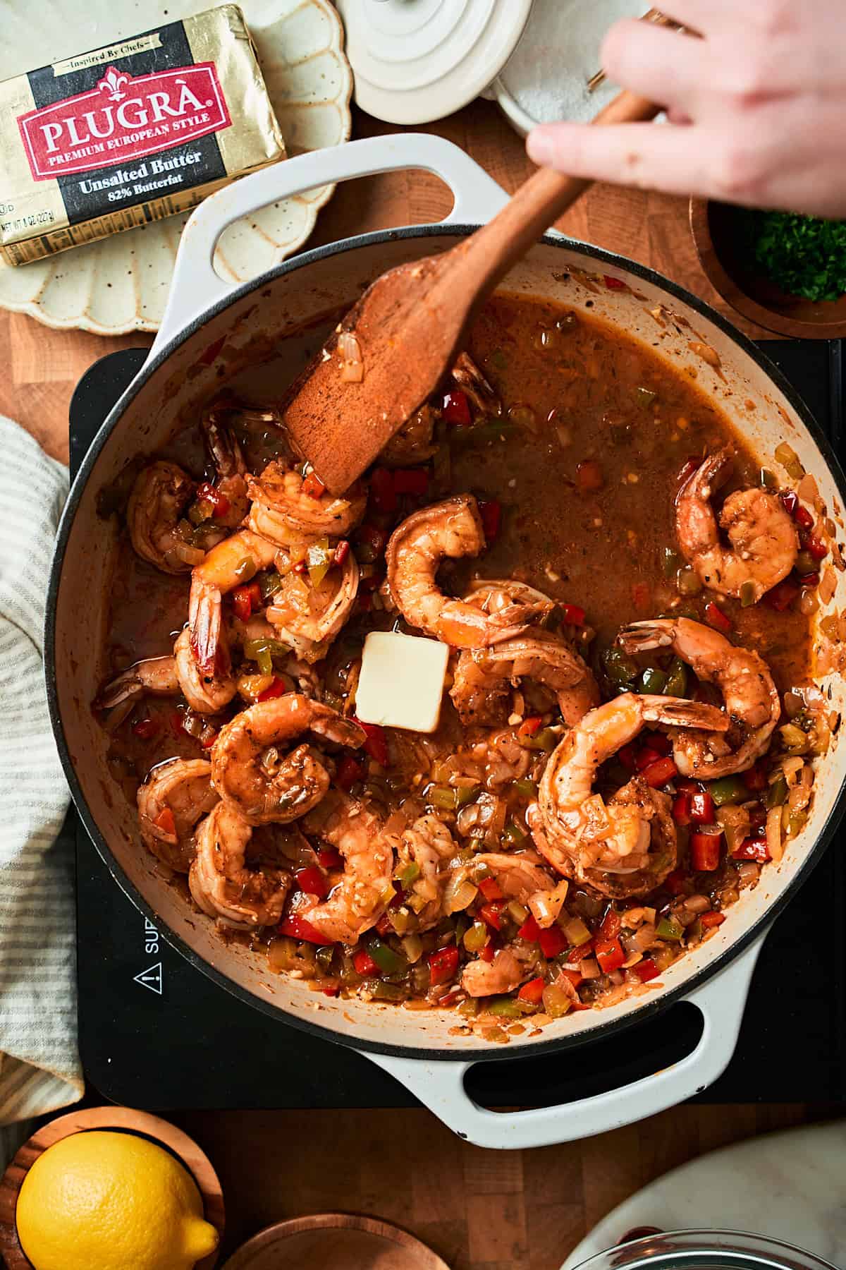 Shrimp in a skillet with a flavorful pan sauce with butter being added.