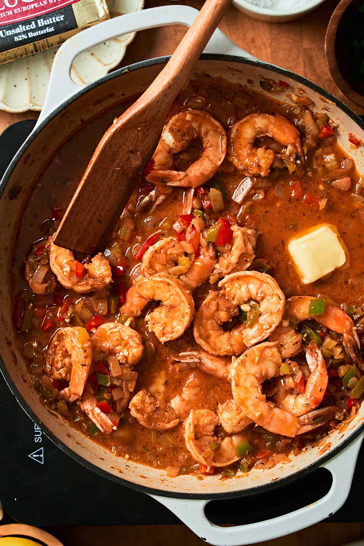 Close up photo of shrimp in a spiced, buttery sauce with a knob of butter getting melted in.
