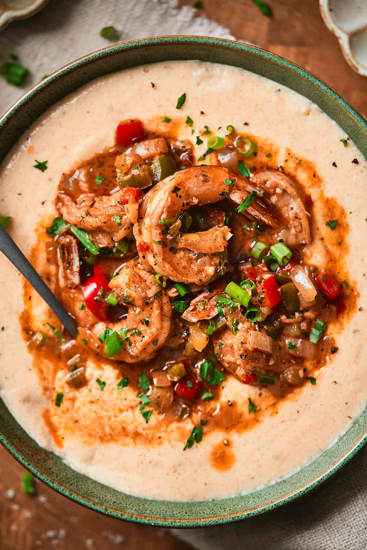 Bowl of creamy grits with shrimp and peppers in a buttery sauce.