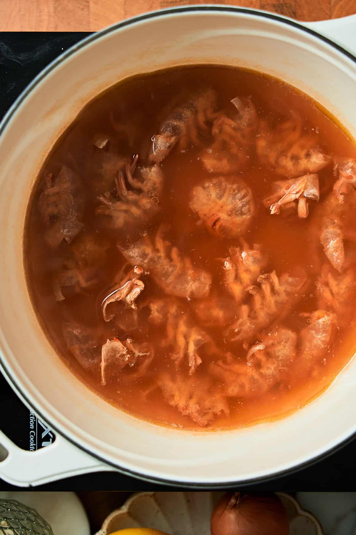 Shrimp shells in chicken broth in a Dutch oven.