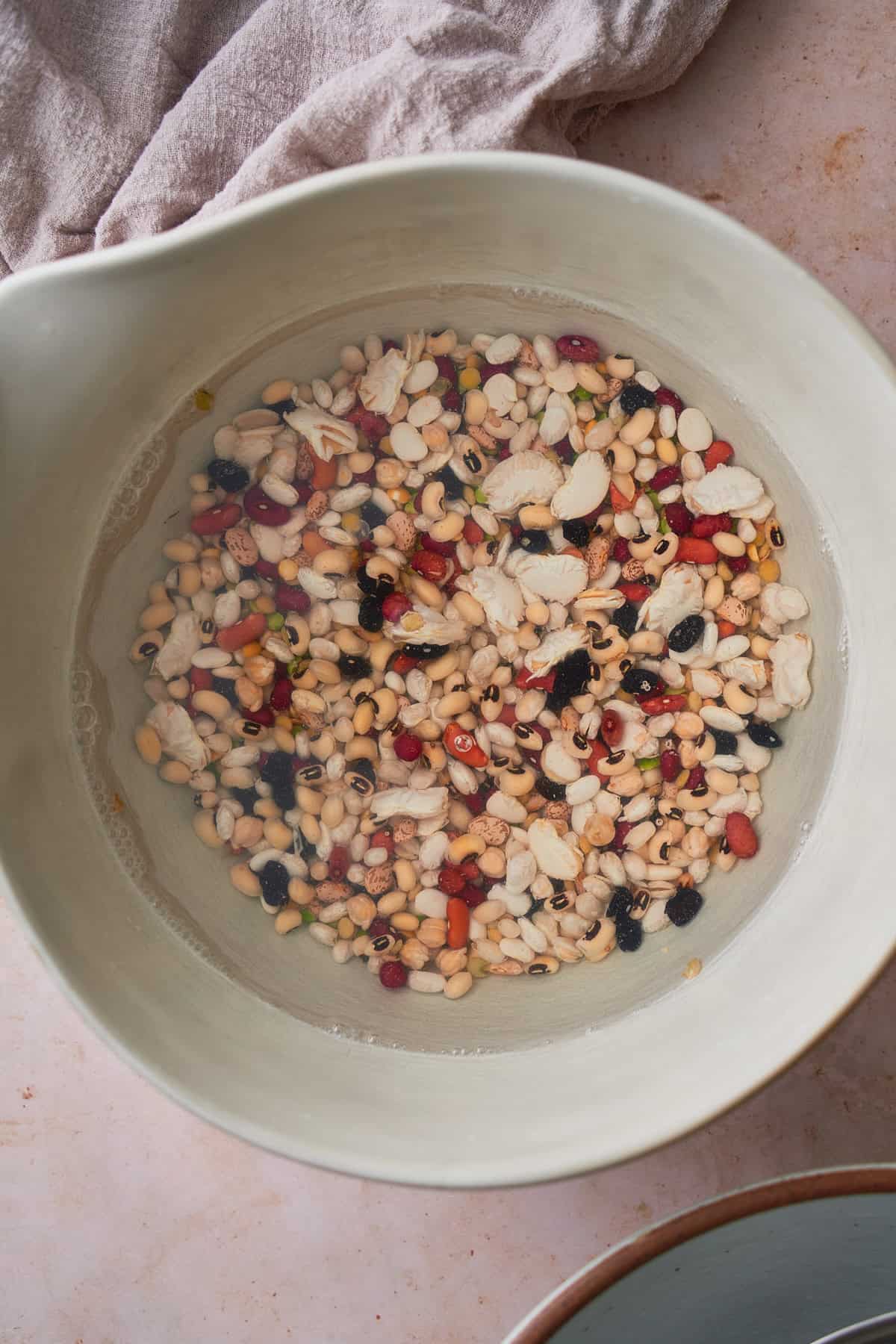 Dried beans being washed in cold water in a large bowl.