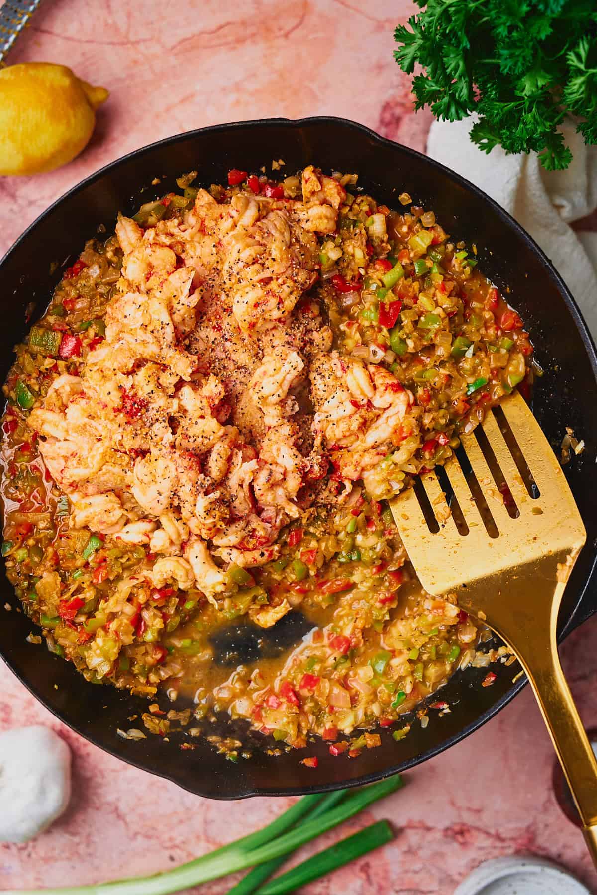 Crawfish meat added to a cast iron skillet with cooked vegetables.