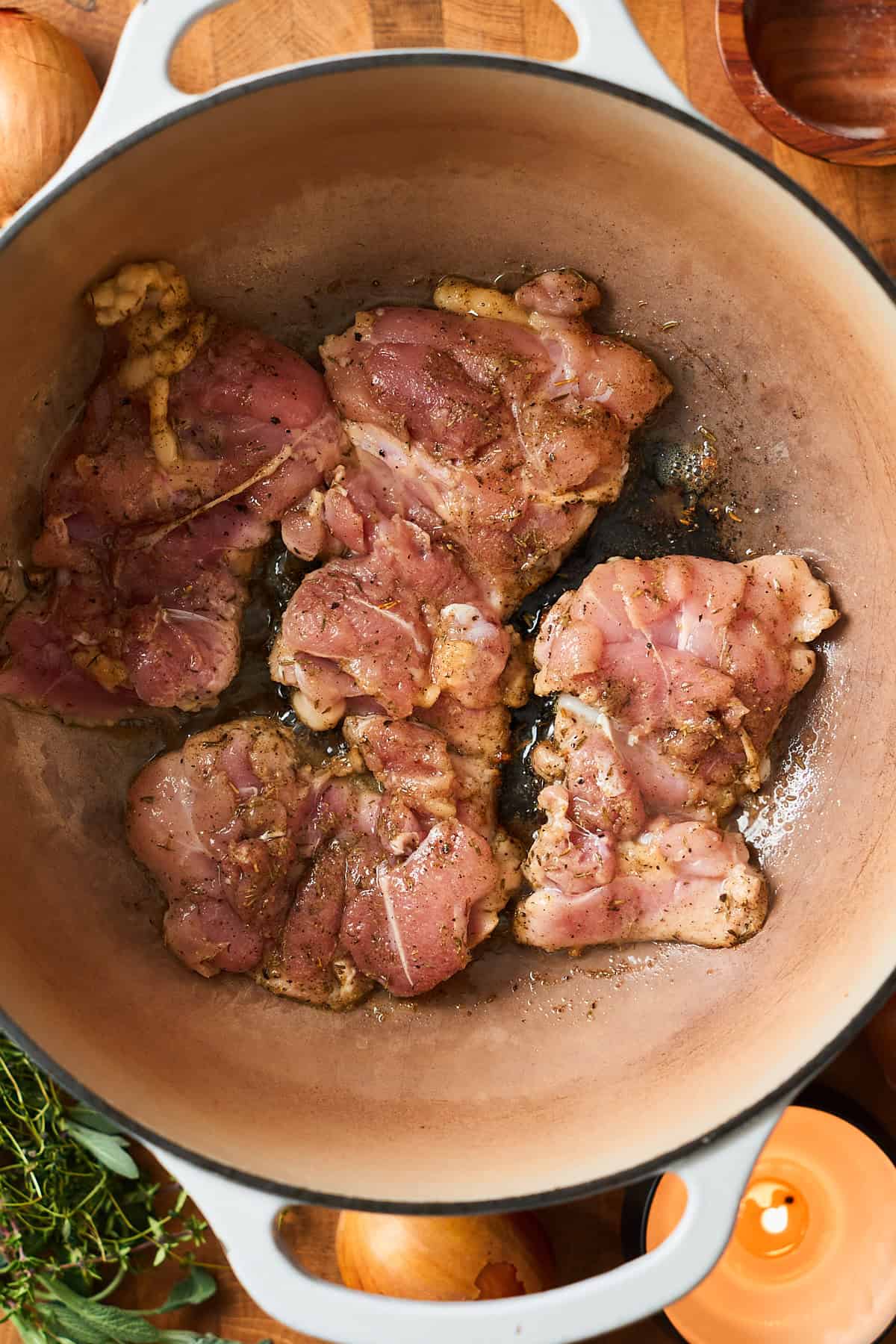 Raw chicken thighs cooking in a Dutch oven.