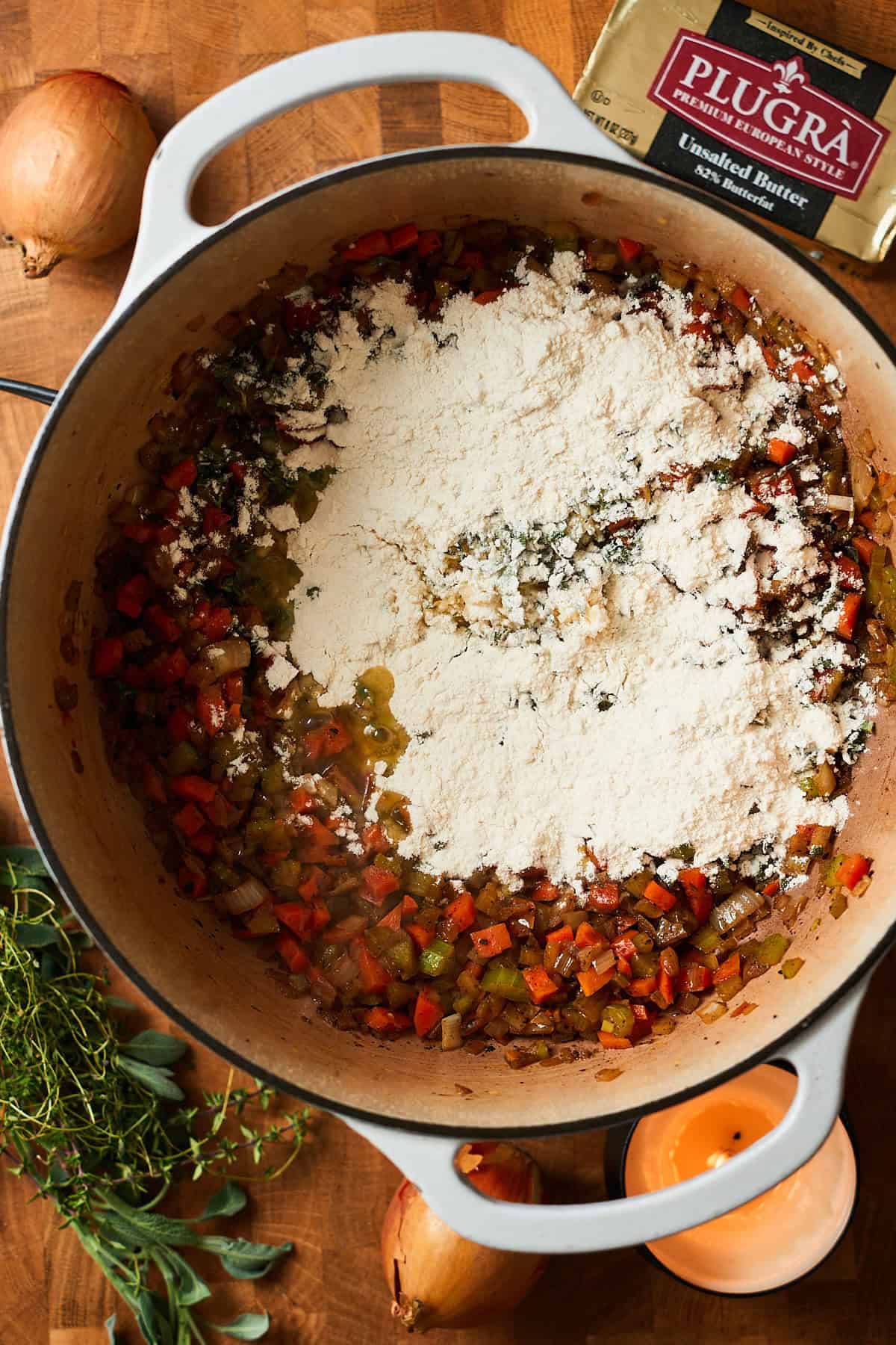 Flour, herbs and garlic added to an enameled Dutch oven.