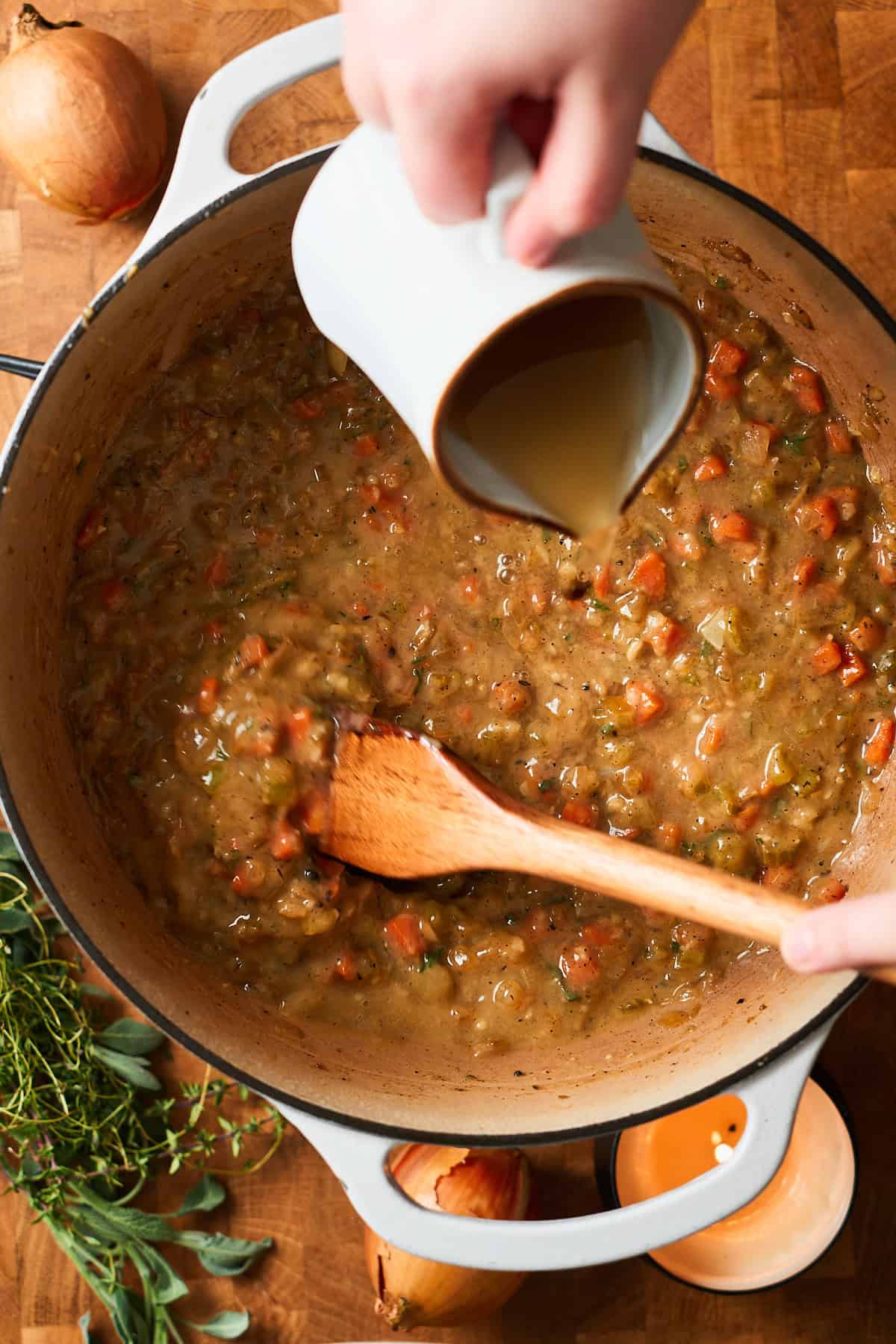 Pouring chicken broth into an enameled Dutch oven to make a chicken stew.