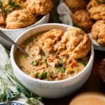 Creamy chicken pot pie soup in a bowl with drop biscuits.