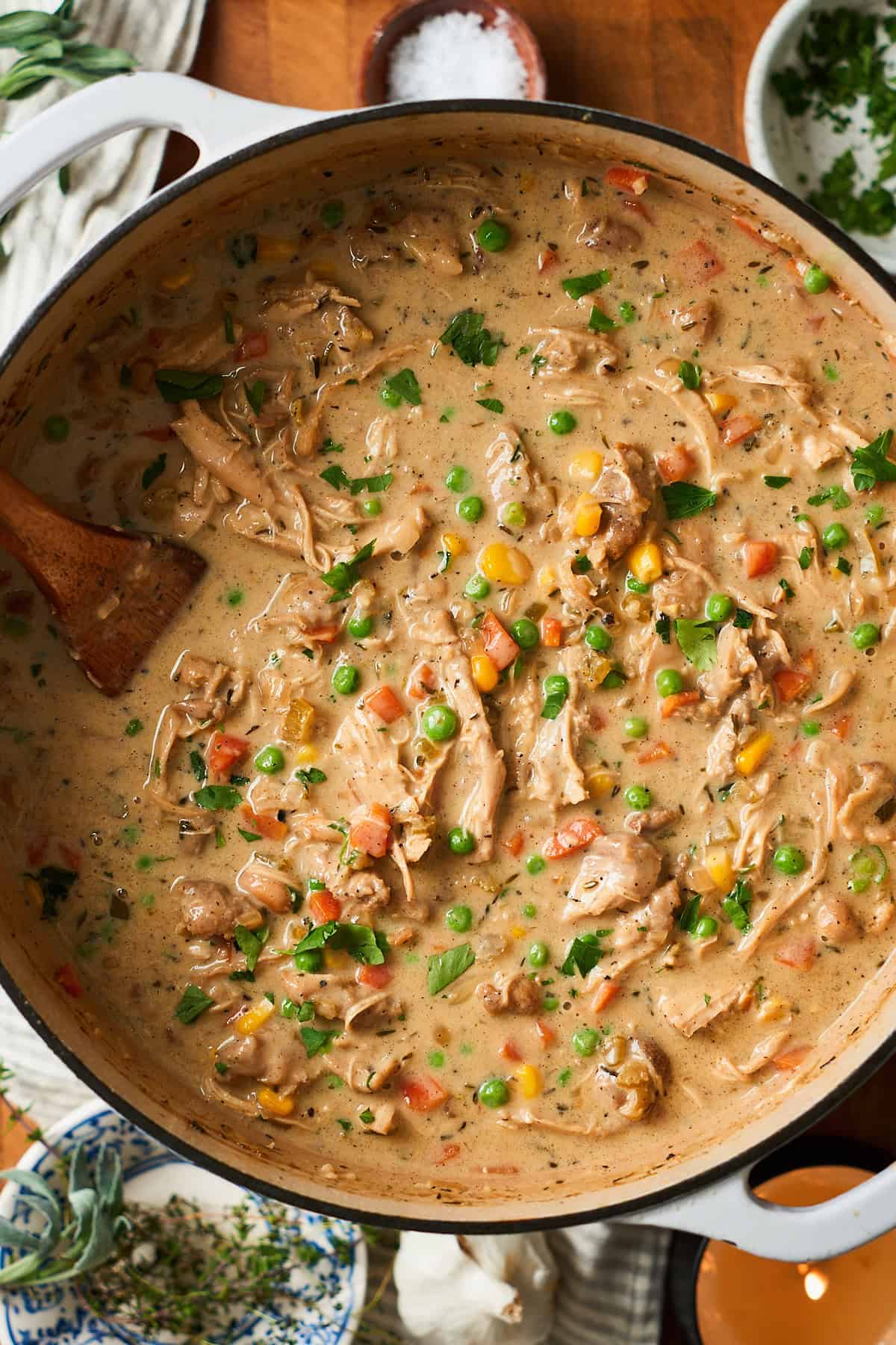Gorgeous pot of creamy chicken pot pie soup with a wooden spoon inside.