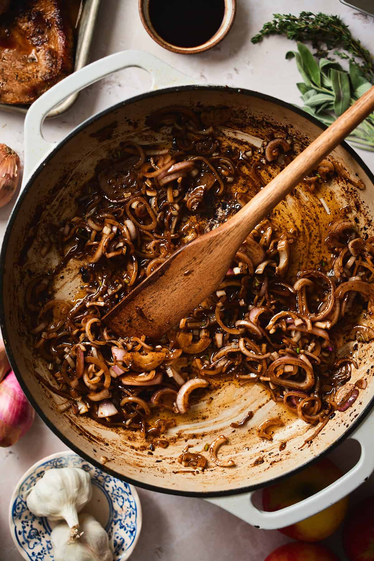 Cooking shallots in a pan and stirring to scrape up the pan bits.