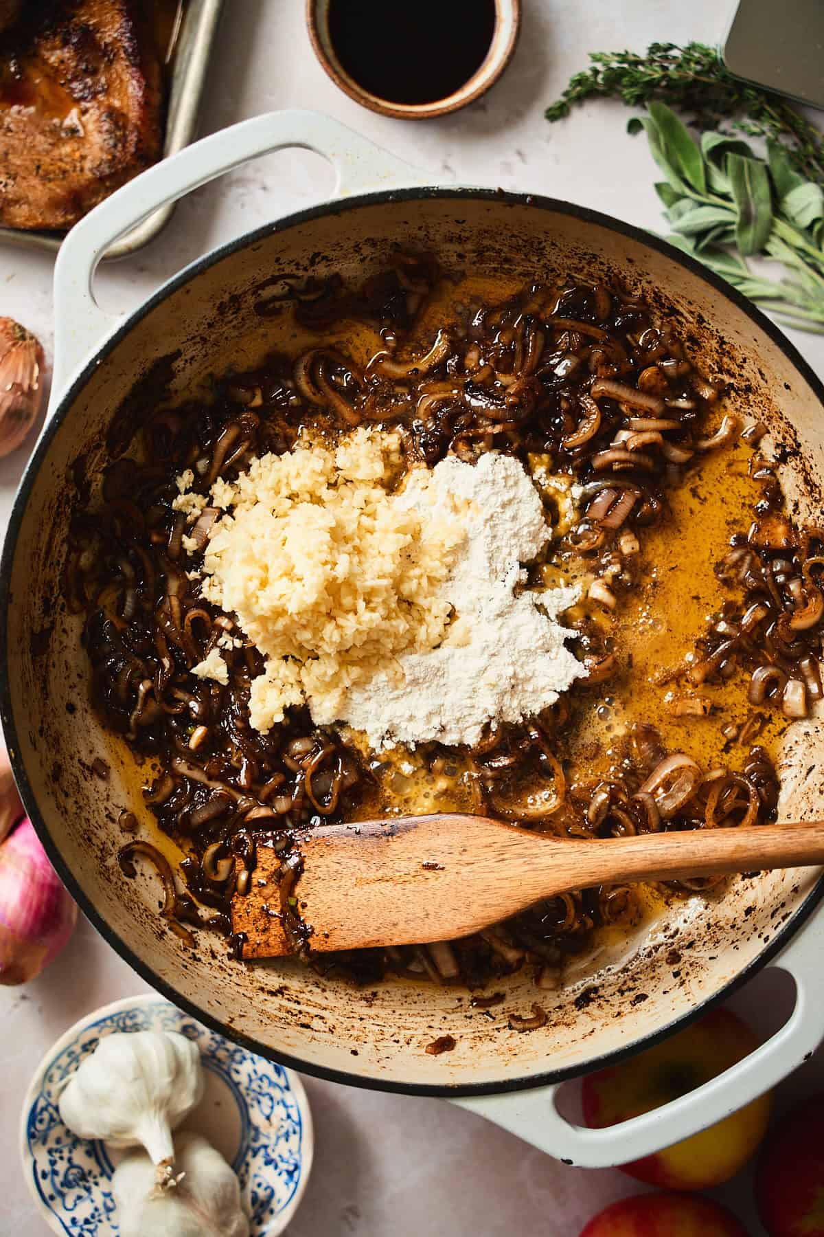 Cooked shallots with flour and garlic added to the pan.