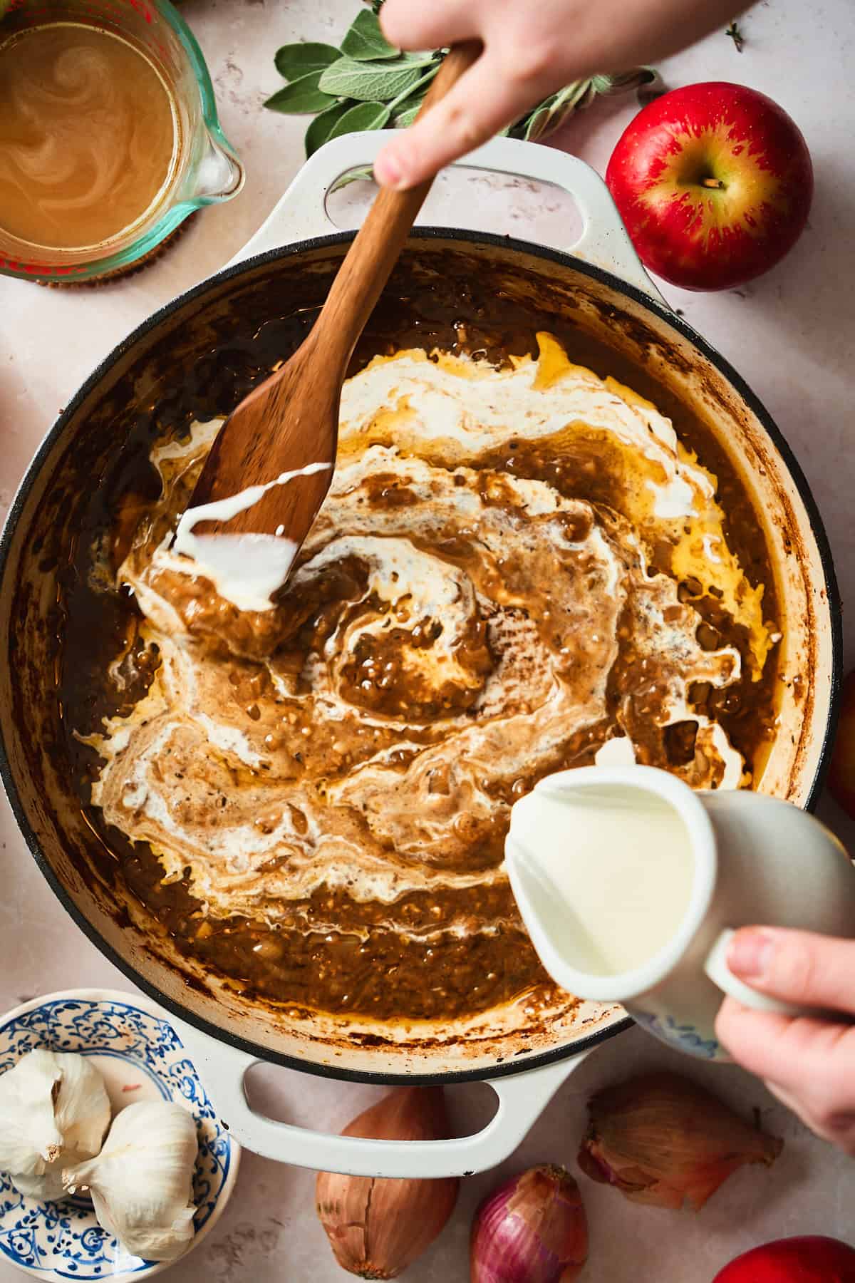 Stirring heavy cream into a skillet full of pan drippings, shallots, and rich gravy.
