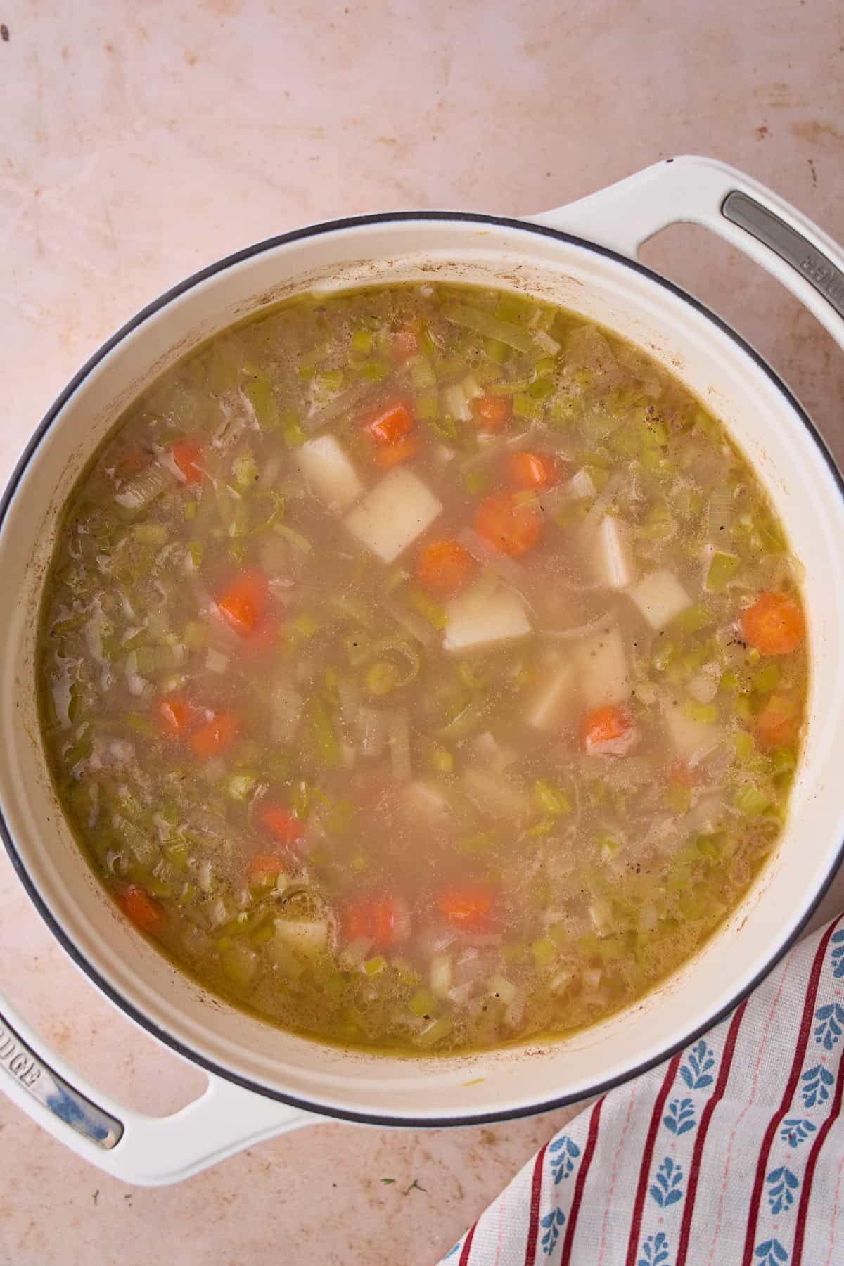 Cooked potatoes and carrots in a broth in a Dutch oven.