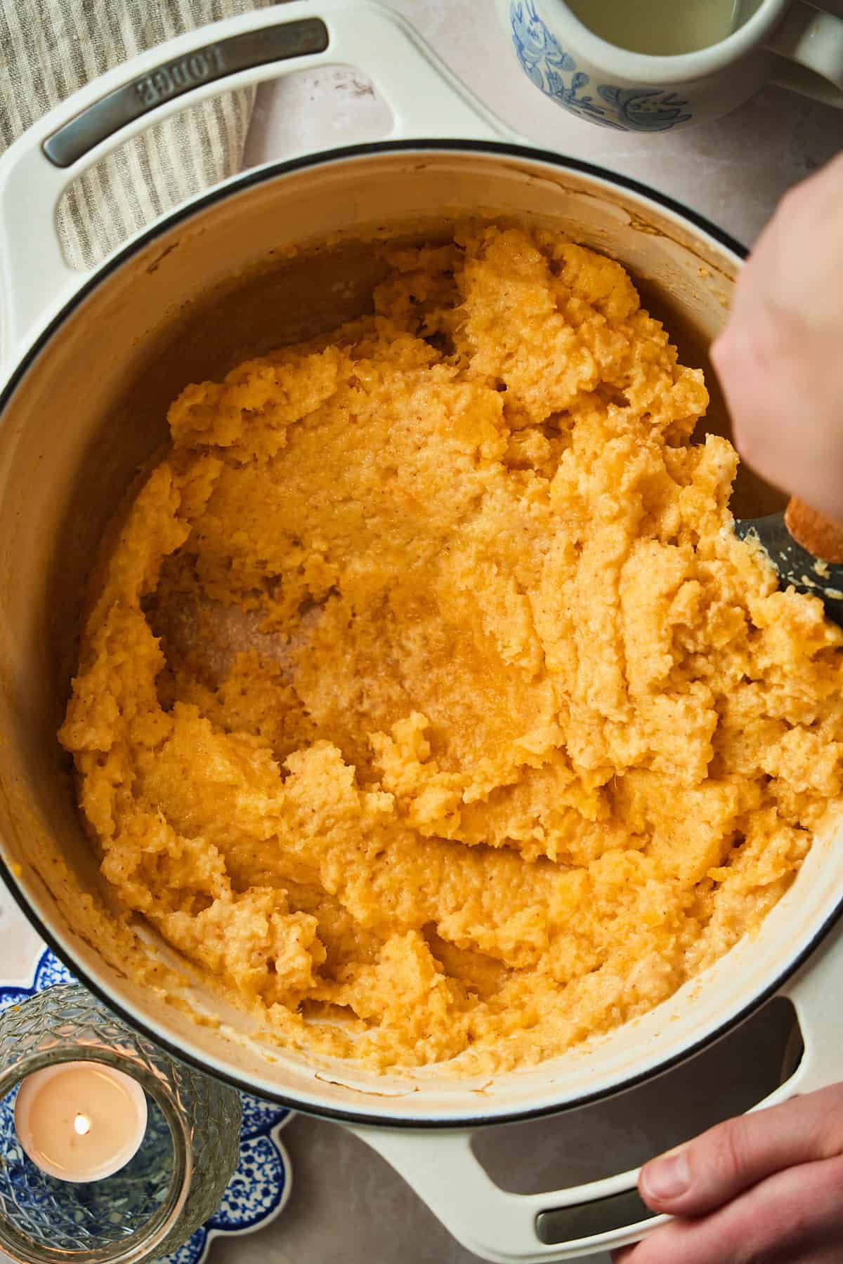 Hand stirring together mashed rutabaga with cream and butter in a Dutch oven.