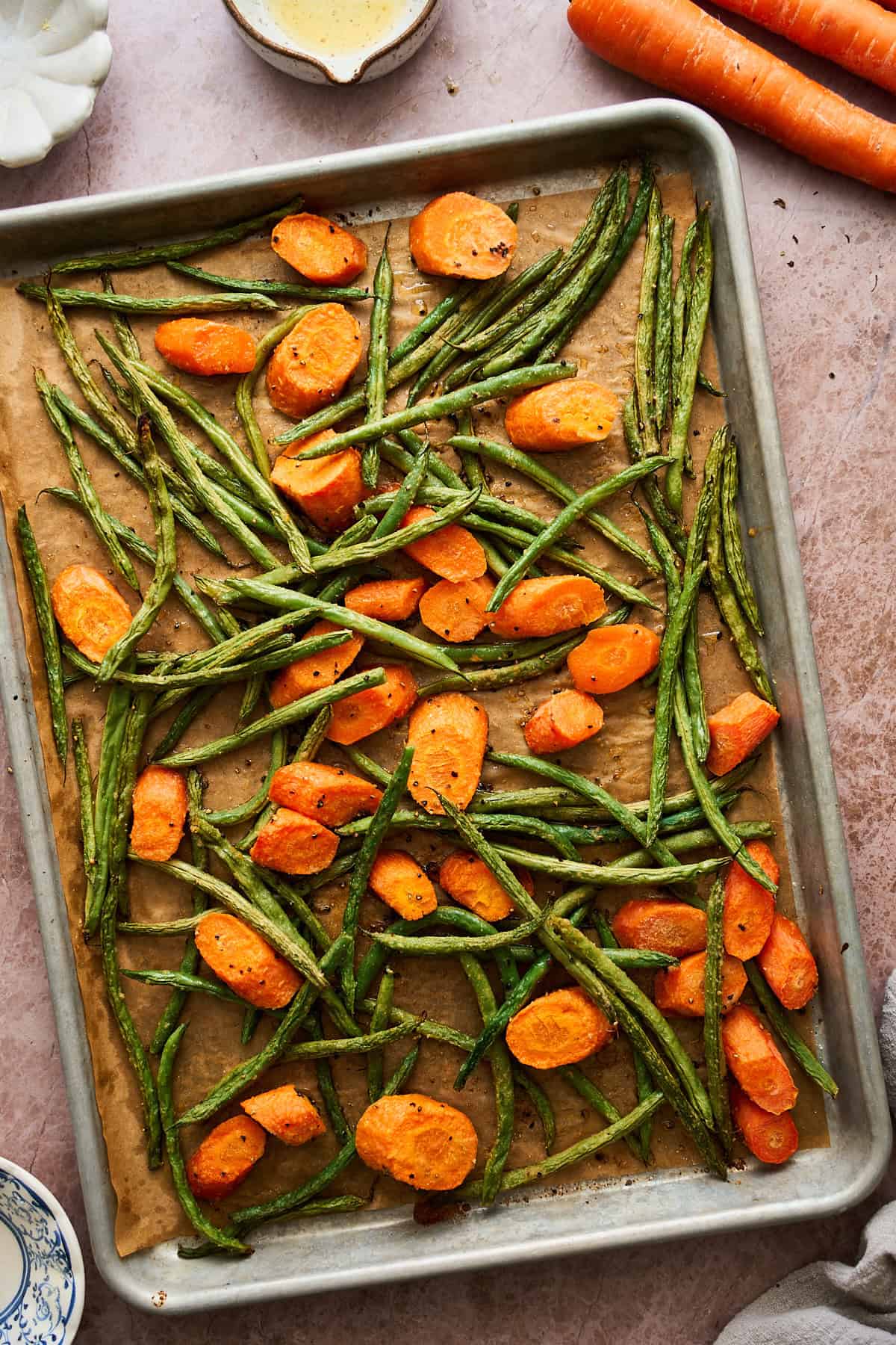 Green beans and carrots on a baking sheet with parchment paper roasted.