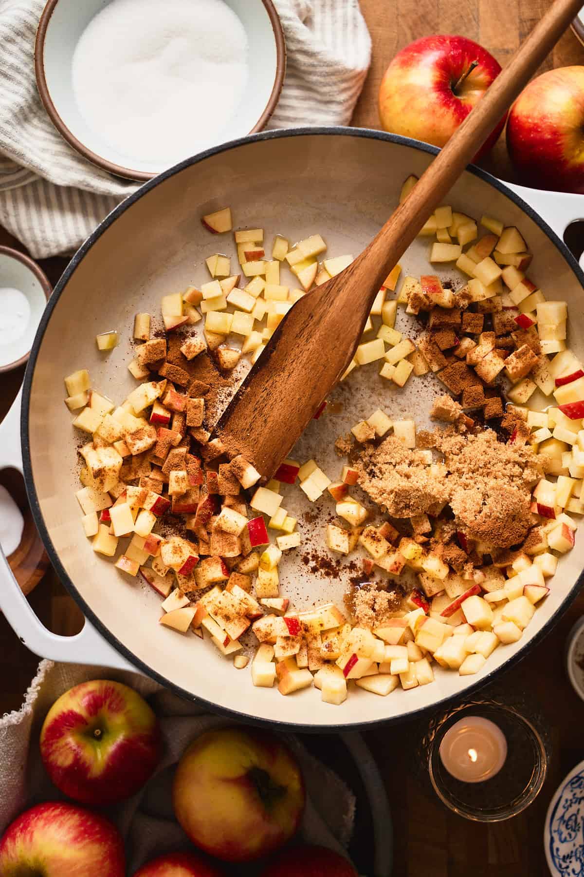 Apple chunks, brown sugar, cinnamon and salt in a skillet with a wooden spoon.