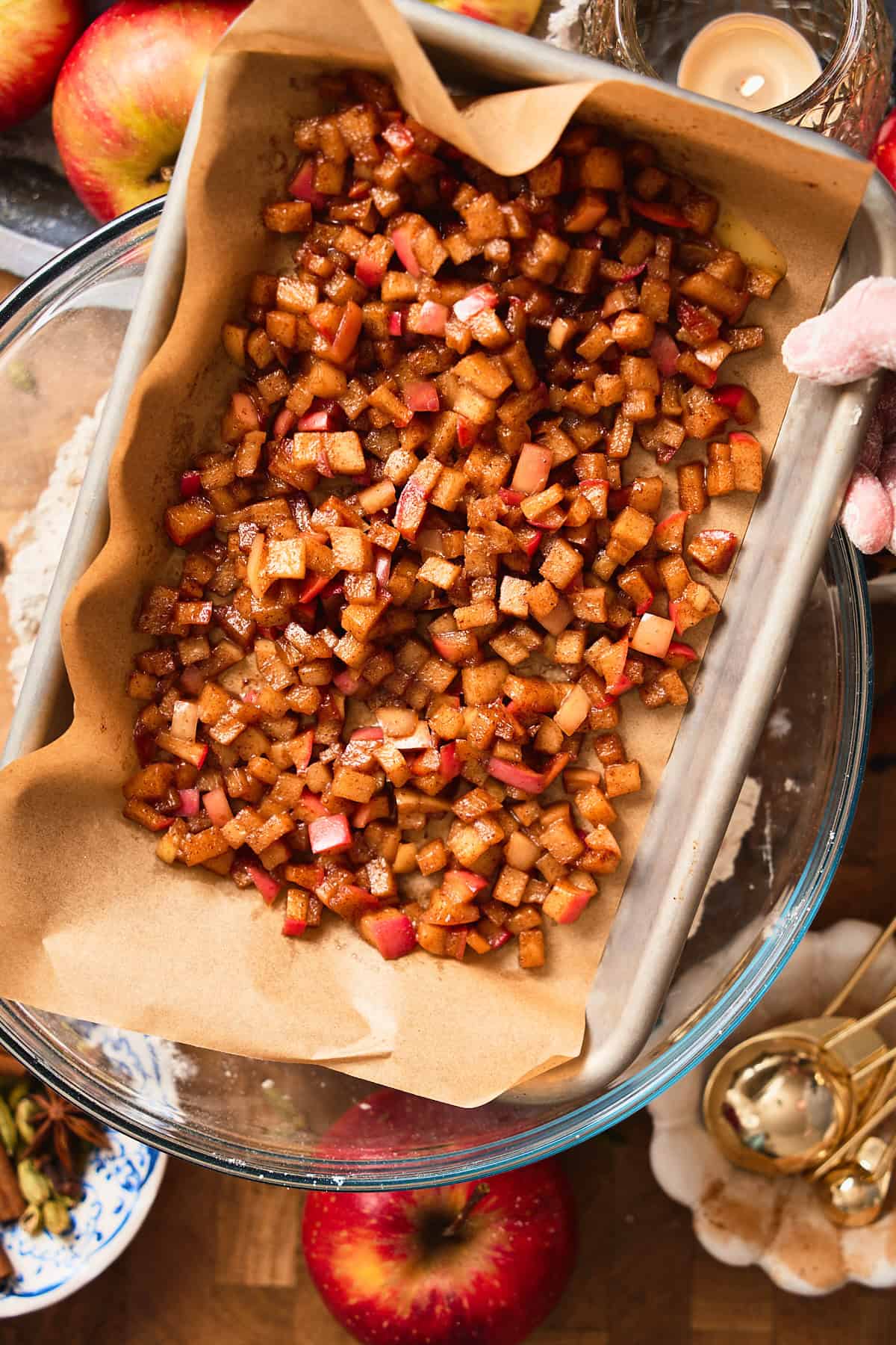 Apples cooling on a tray lined with parchment paper with a mixing bowl underneath.