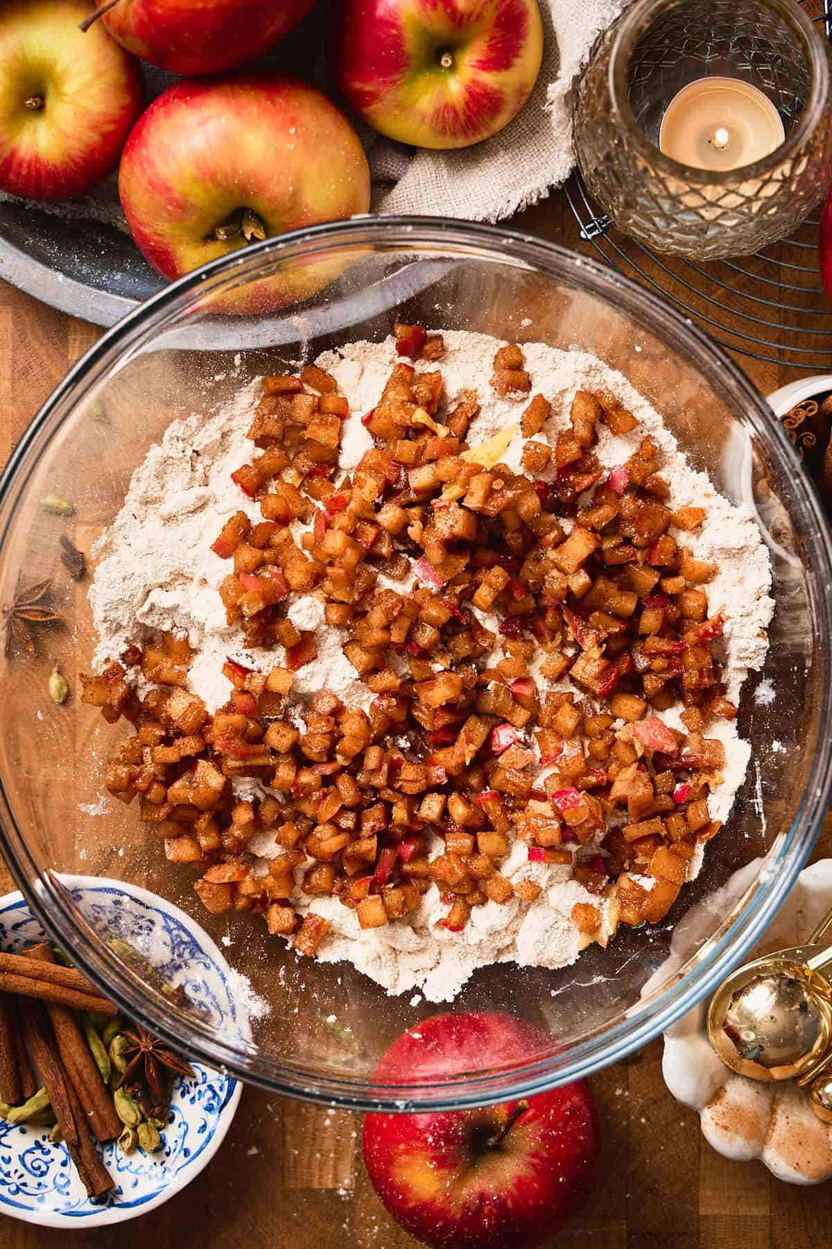 Apple pieces in a large bowl with flour, butter, and other ingredients surrounding.